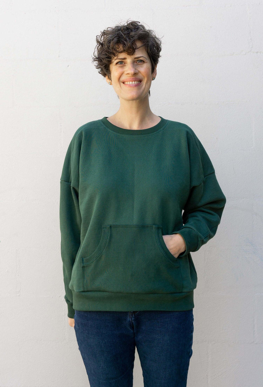 Woman wearing the Ali Sweatshirt sewing pattern from Sew DIY on The Fold Line. A sweatshirt pattern made in medium-weight knit fabrics, featuring drop shoulders, dolman sleeves, shoulder yoke, crew neck and kangaroo pocket.
