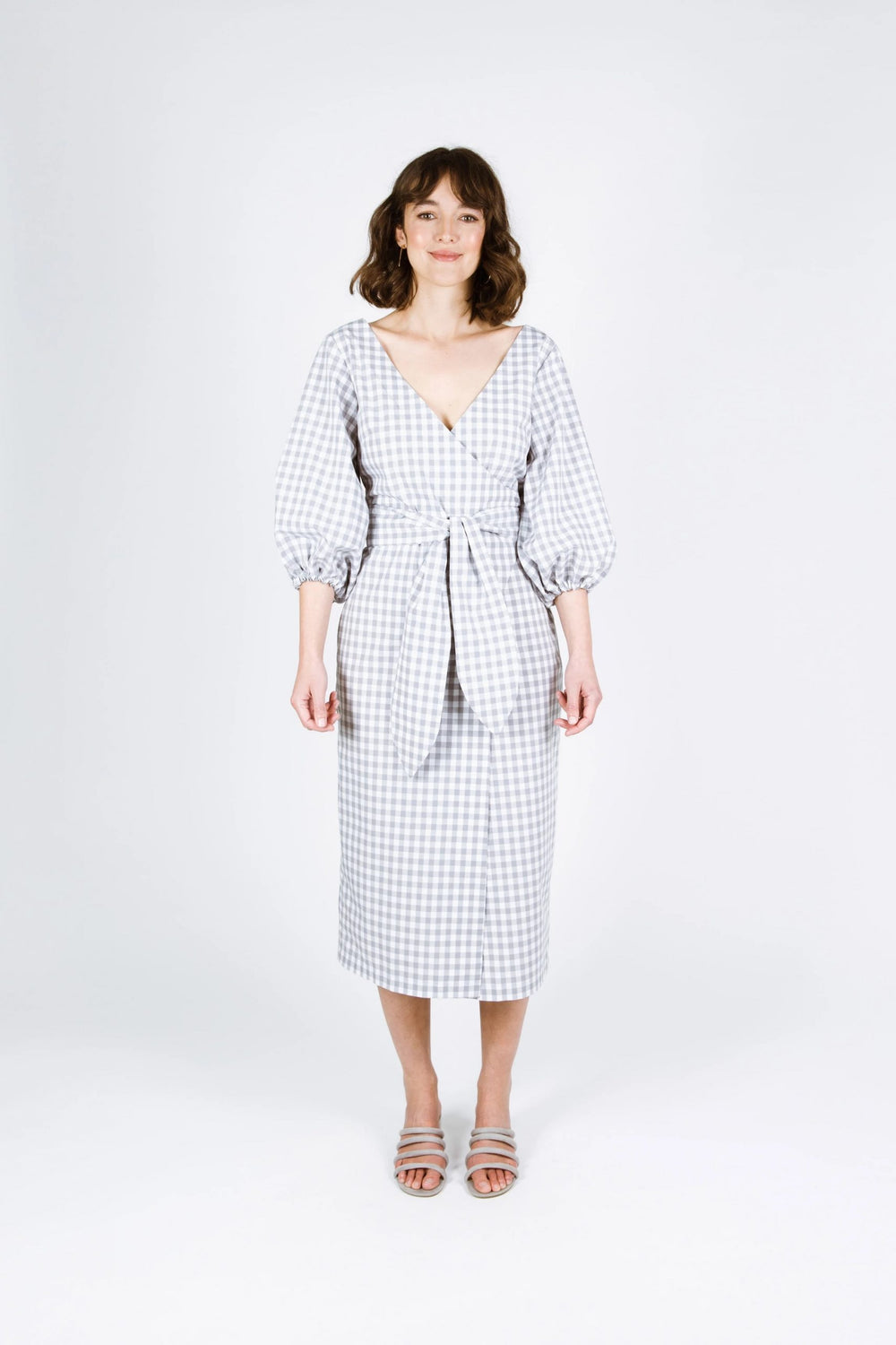 Woman wearing the Aura Dress sewing pattern from Papercut Patterns on The Fold Line. A dress pattern made in cotton, linen, rayon or blend fabrics, featuring a deep V-neckline, midi length, ¾ length balloon sleeves, wrap style and self-fabric belt closure