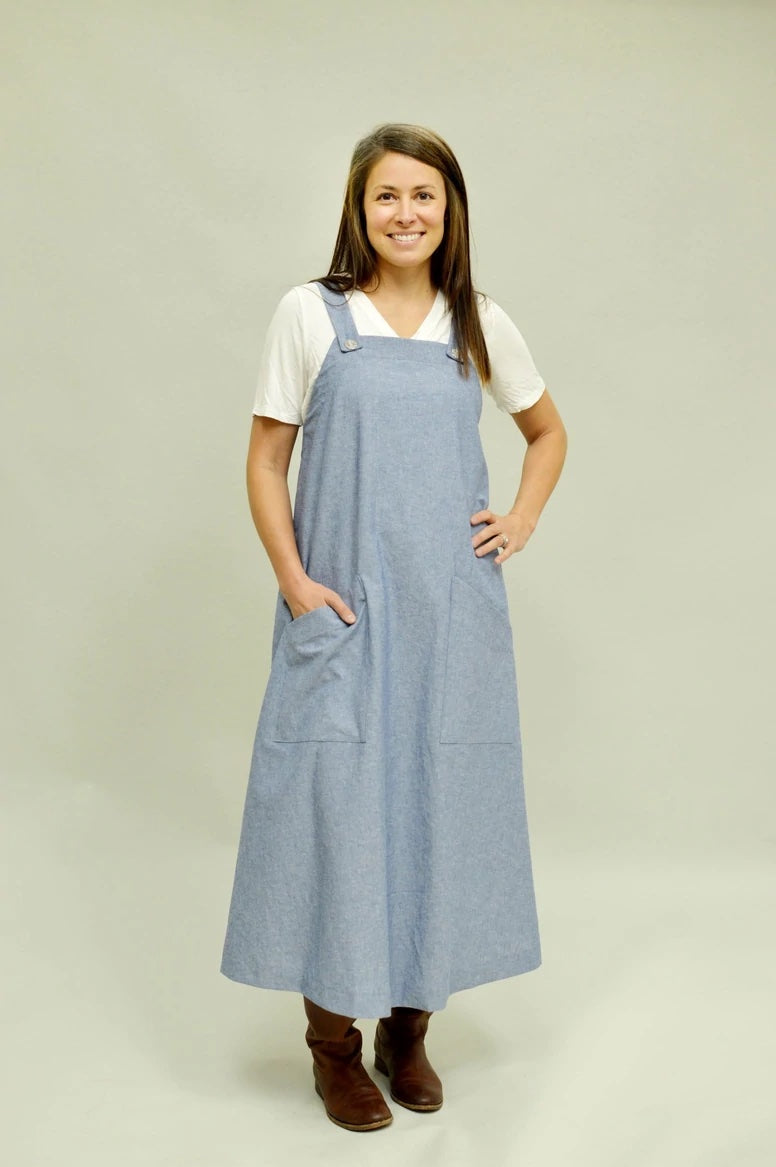 Woman wearing the Pinafore Dress sewing pattern from Folkwear on The Fold Line. A pinafore pattern made in cotton broadcloth, chambray, poplin, linen, wool, sturdy knits, wool, denim, twill, or canvas fabrics, featuring a low-calf-length, two front patch