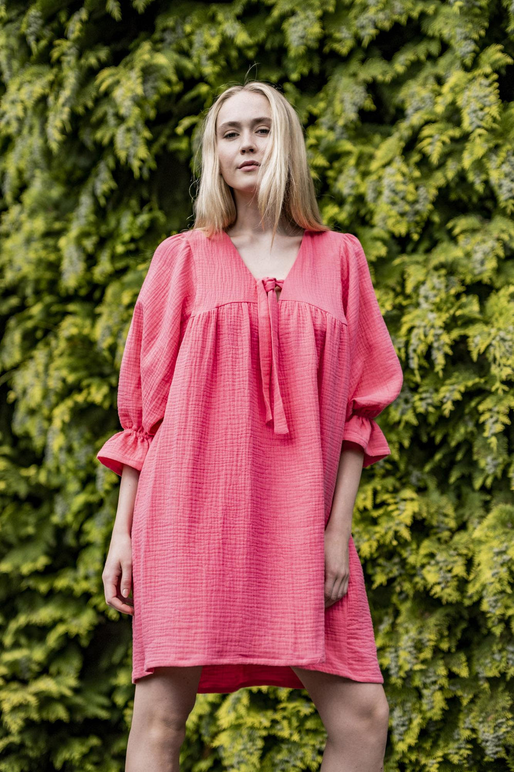 Woman wearing the Blossom Dress sewing pattern from Fibre Mood on The Fold Line. A dress pattern made in cotton voile, linen, double gauze, poplin, chambray, and seersucker fabrics, featuring an oversized silhouette, deep V-neckline with bow, front and ba