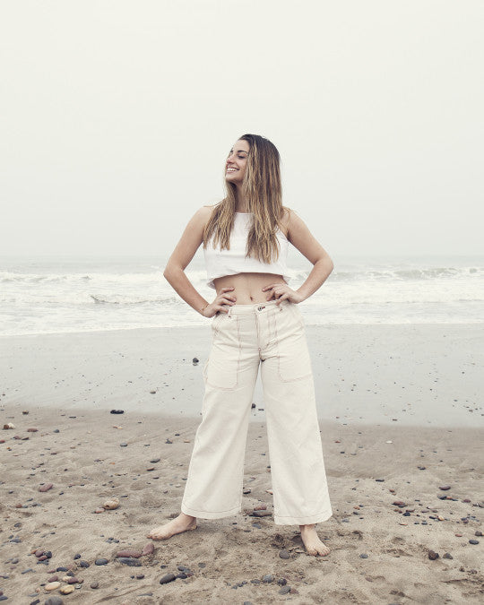 Woman wearing the Albors Trousers sewing pattern from Pauline Alice on The Fold Line. A workwear-inspired trousers pattern made in denim, linen, twill, corduroy, or cotton canvas fabric, featuring a natural waist with adjustment tabs, fly front, front and back pockets, tool pockets, hammer loop, wide leg, and cropped length.