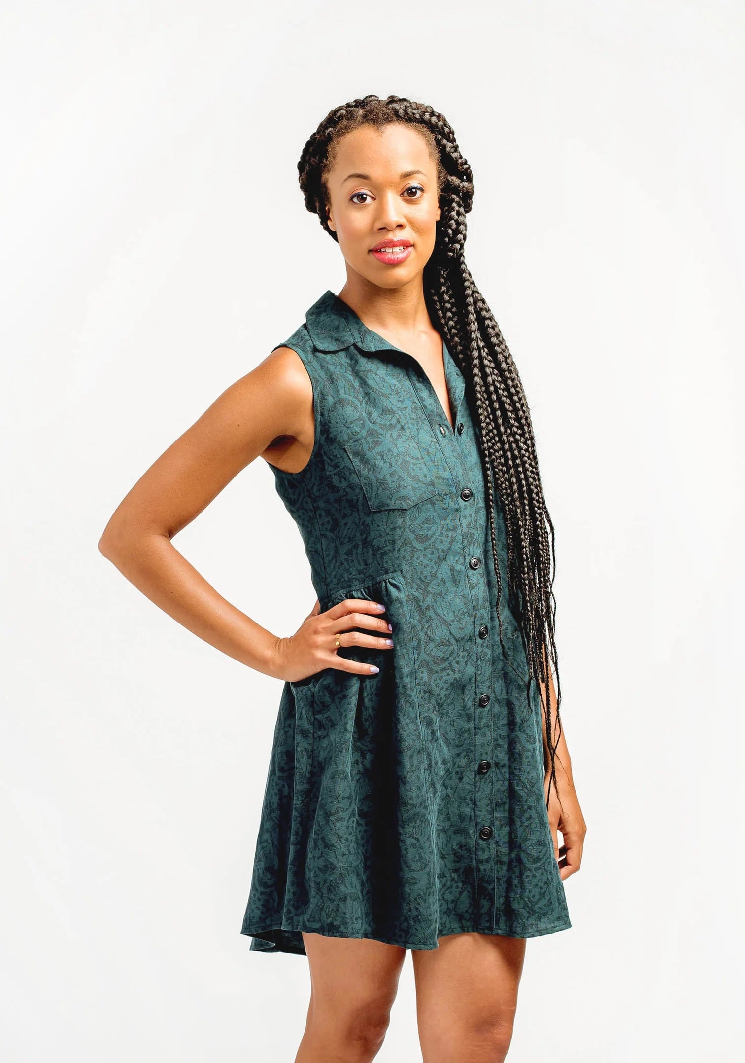 Woman wearing the Alder Shirtdress sewing pattern from Grainline Studio on The Fold Line. A dress pattern made in silk charmeuse, crepe de chine, cotton shirting, poplin, chambray, sateen, denim, linen, linen blends, or flannel fabric, featuring bust darts, two breast pockets, a gathered skirt at the sides and back, curved hem, and mini length.