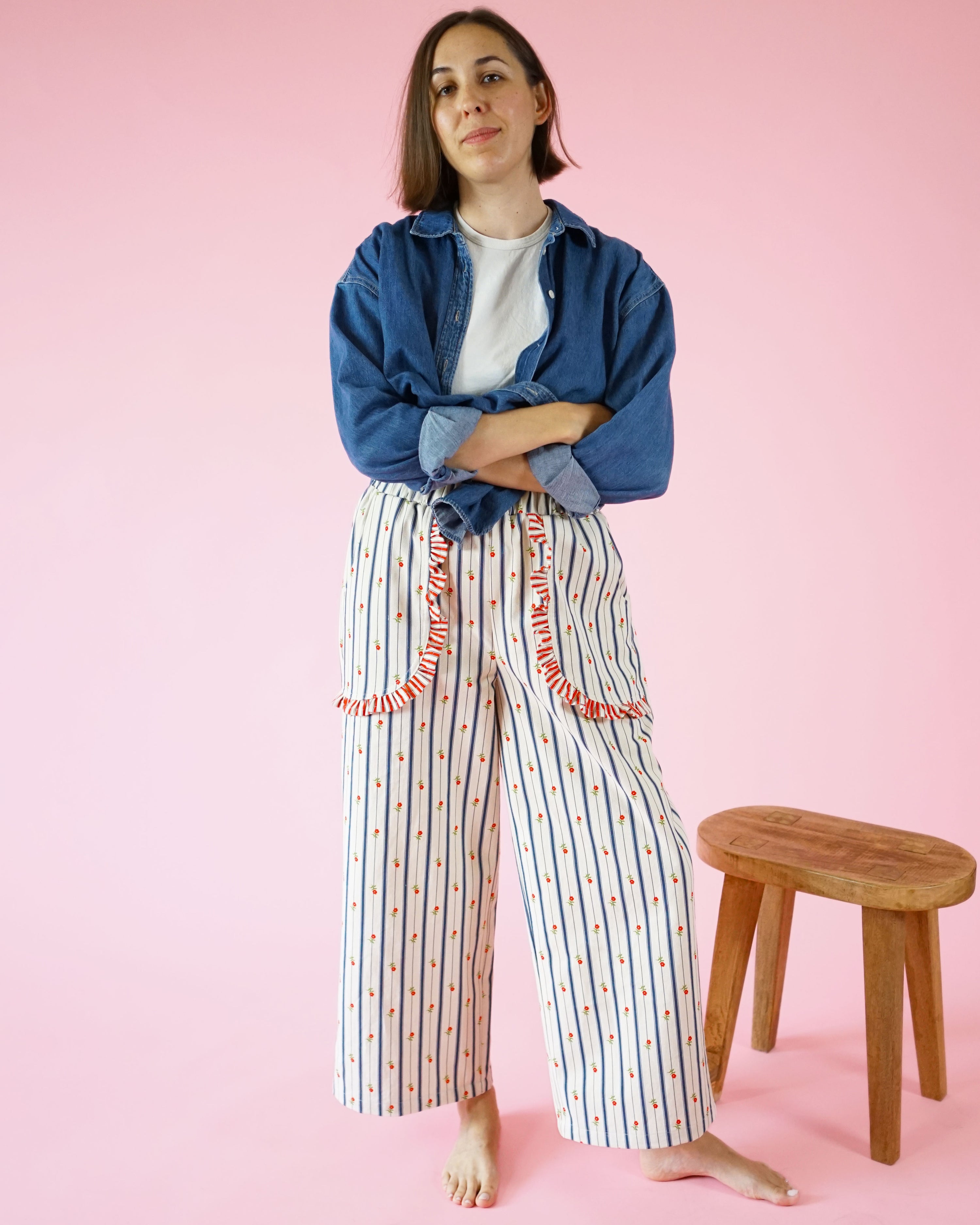 Woman wearing the Apron Pocket Pants sewing pattern from Matchy Matchy Sewing Club on The Fold Line. A trousers pattern made in cotton or linen fabric, featuring a high-waisted elastic waistband, pockets with ruffles, and a wide leg.