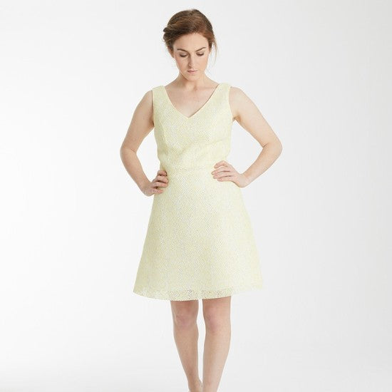 Woman wearing the Armelle Dress sewing pattern from Coralie Bijasson on The Fold Line. A sleeveless dress pattern made in cotton, linen, wild silk, ottoman, brocade, or denim fabric, featuring V-necklines at the front and back, princess seams, an A-line skirt, and above knee length.
