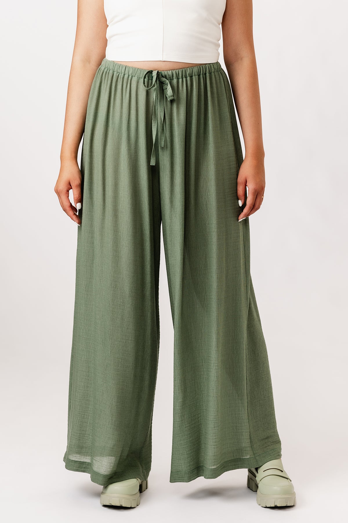 Woman wearing the Aulio Elastic Waist Trousers sewing pattern from Named on The Fold Line. A pants pattern made in viscose challis or crepe, cotton lawn, or washed linen fabric, featuring a high elasticated waist, drawstring, and wide legs.