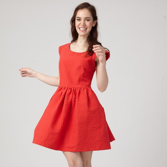 Woman wearing the Aurore Dress sewing pattern from Coralie Bijasson on The Fold Line. A dress pattern made in cotton, linen, brocade, silk dupioni, ottoman, or denim fabric, featuring a round neckline, short raglan sleeves, gathered skirt, and mini length.