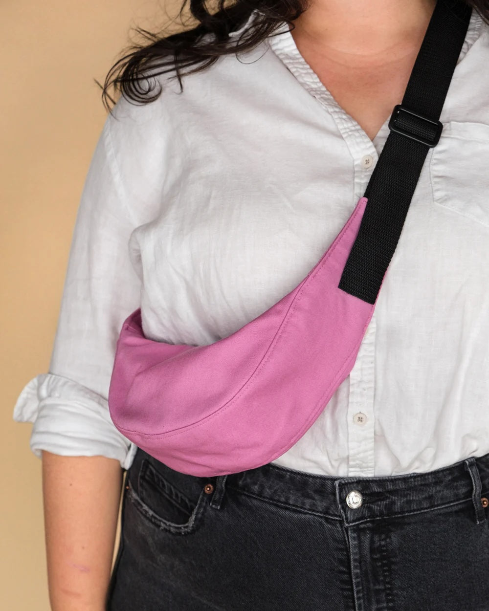 Woman wearing the Baby Bestie Bag (Expansion Pack) sewing pattern from BF Patterns on The Fold Line. A cross-body bag pattern made in denim, canvas, twill, heavyweight nylon, ripstop, leather, or vinyl fabric, featuring a banana shape, zip closure, and webbing strap.