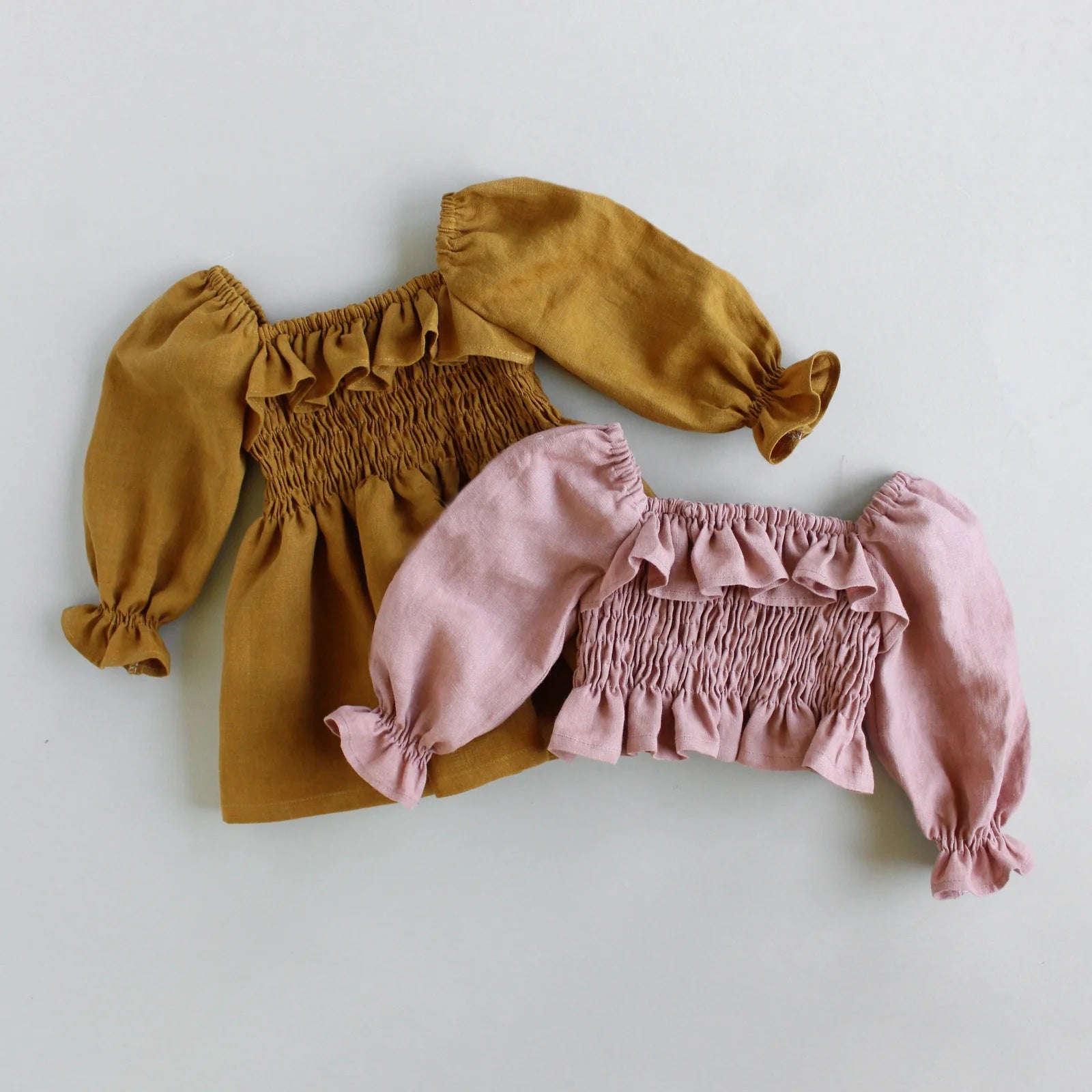 The Baby/Child Nova Dress and Top sewing pattern from Oh Me Oh My Sewing on The Fold Line. A dress or top pattern made in voile, lawn, double or single gauze, quilting cotton, or washed linen fabric, featuring a shirred bodice with a ruffle and puff sleeves.