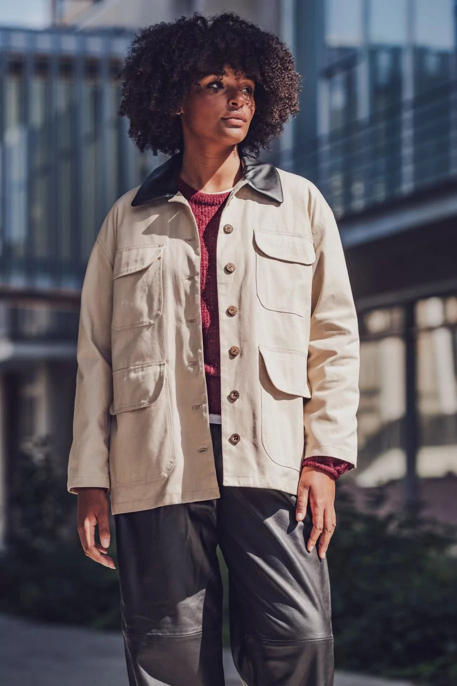 Woman wearing the Barbara Jacket sewing pattern from Fibre Mood on The Fold Line. A barn jacket pattern made in cotton twill or canvas fabric, featuring a contrast collar, button front, and pockets with flaps.