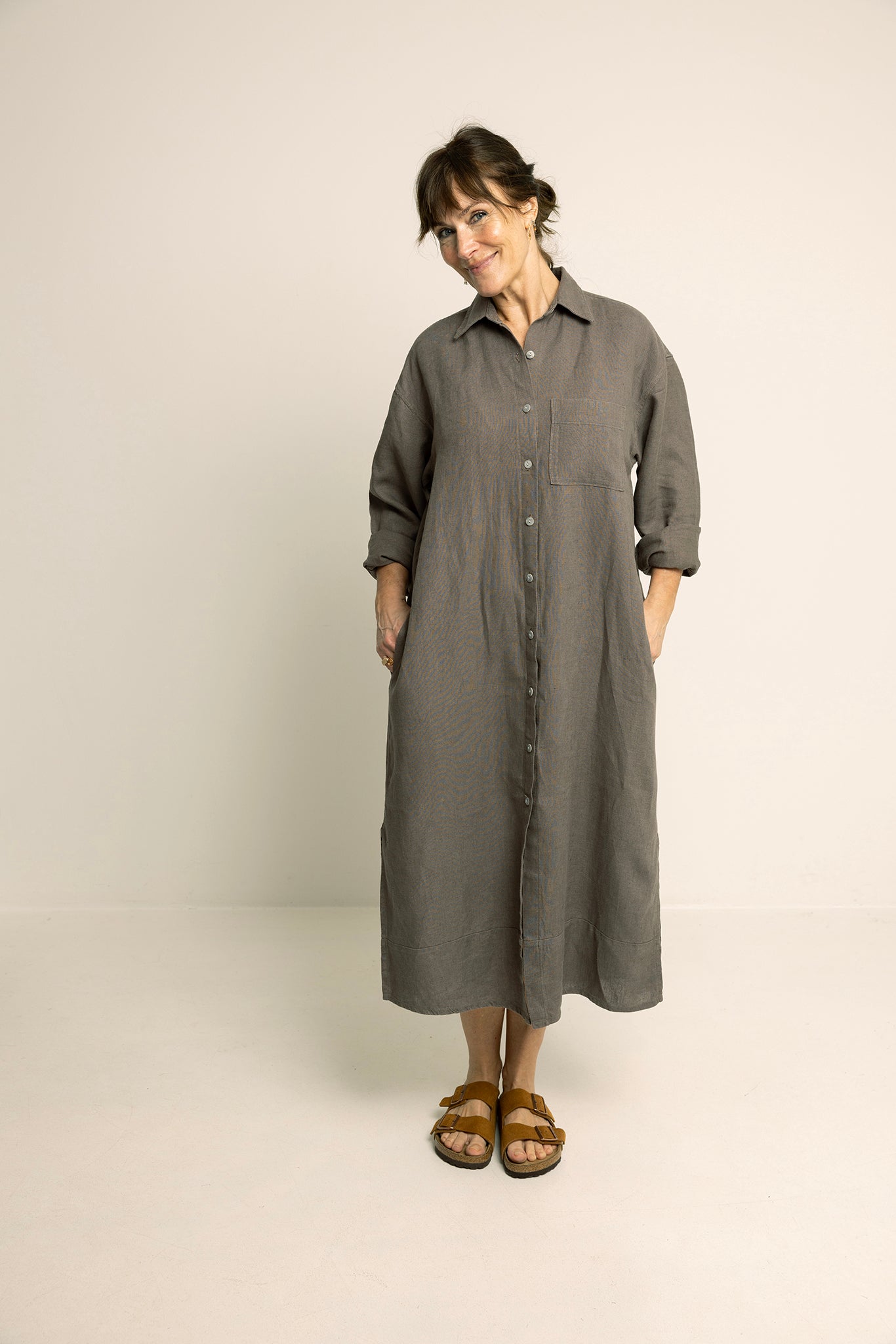 Woman wearing the Big Shirt Dress sewing pattern from Wardrobe by Me on The Fold Line. A shirt dress pattern made in cotton voile, linen, poplin, or chambray fabric, featuring an oversized fit, collar and collar stand, dropped shoulders, voluminous sleeves with cuffs, back yoke with gathers, button front, and side seam pockets.