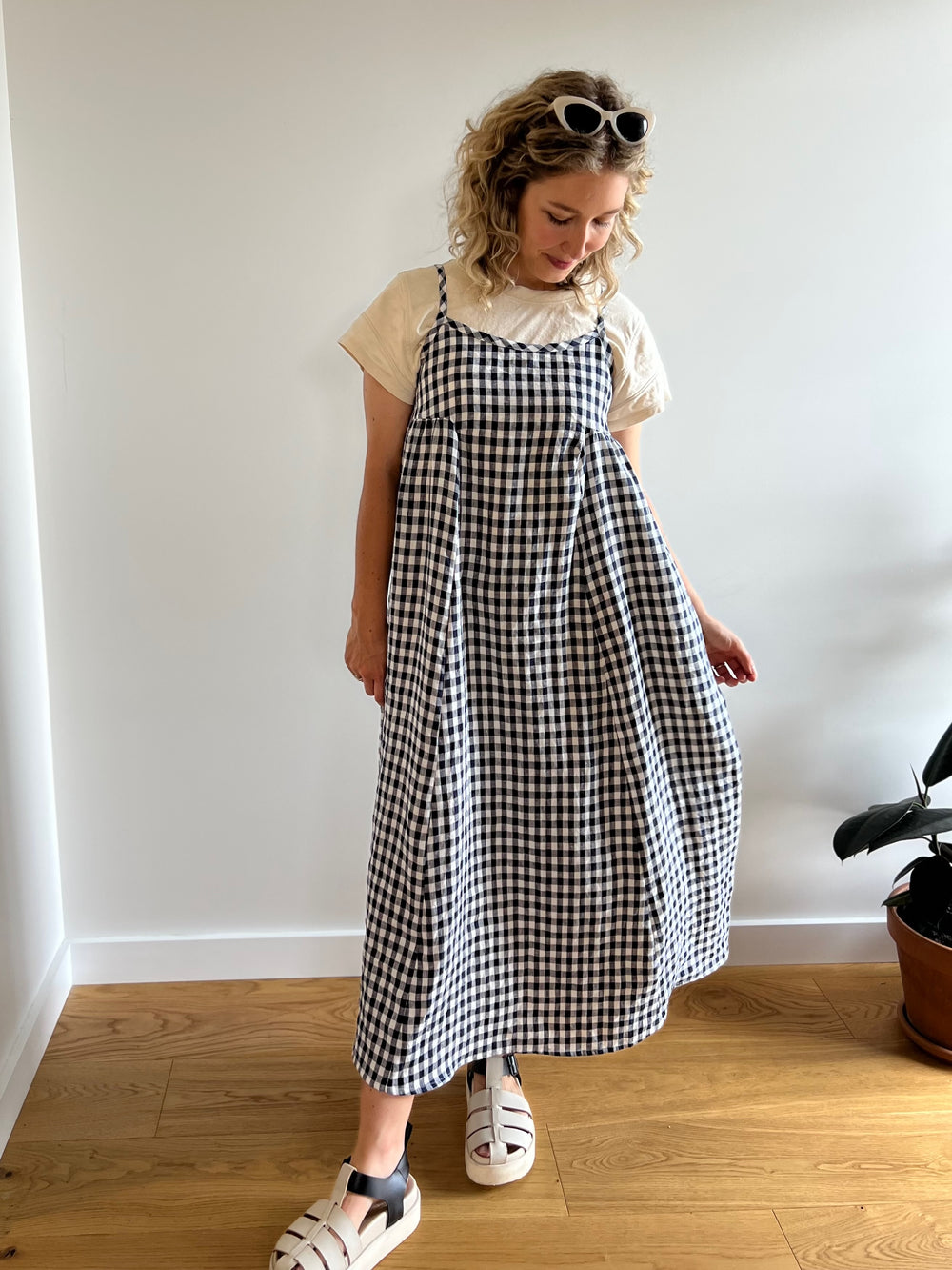 Woman wearing the Bobbie Dress sewing pattern from Elle Stitch on The Fold Line. A dress pattern made in linen, crinkle linen, cotton poplin, cotton lawn, cotton linen blend or linen rayon blend fabric, featuring gathered side panels, tie-up spaghetti straps, and a midi length.