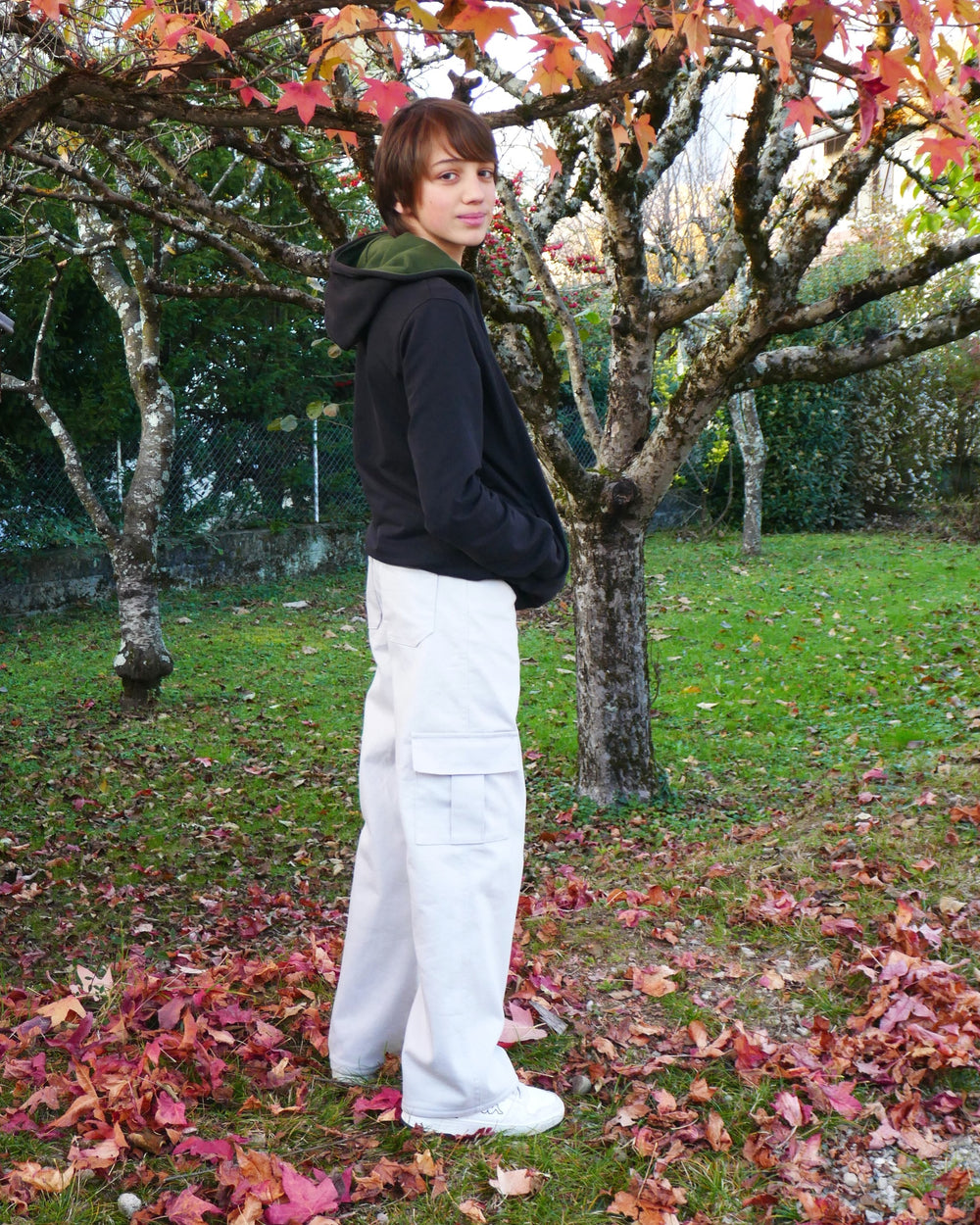 Boy wearing the Child/Teen Buffalo Cargo Pants from Petits D'om on The Fold Line. A pants pattern made in denim or twill fabric, featuring a zipper fly and buttoned waistband, front pockets with a coin pocket, back patch pockets with a hammer loop, side (cargo) pockets, belt loops, and rivets.