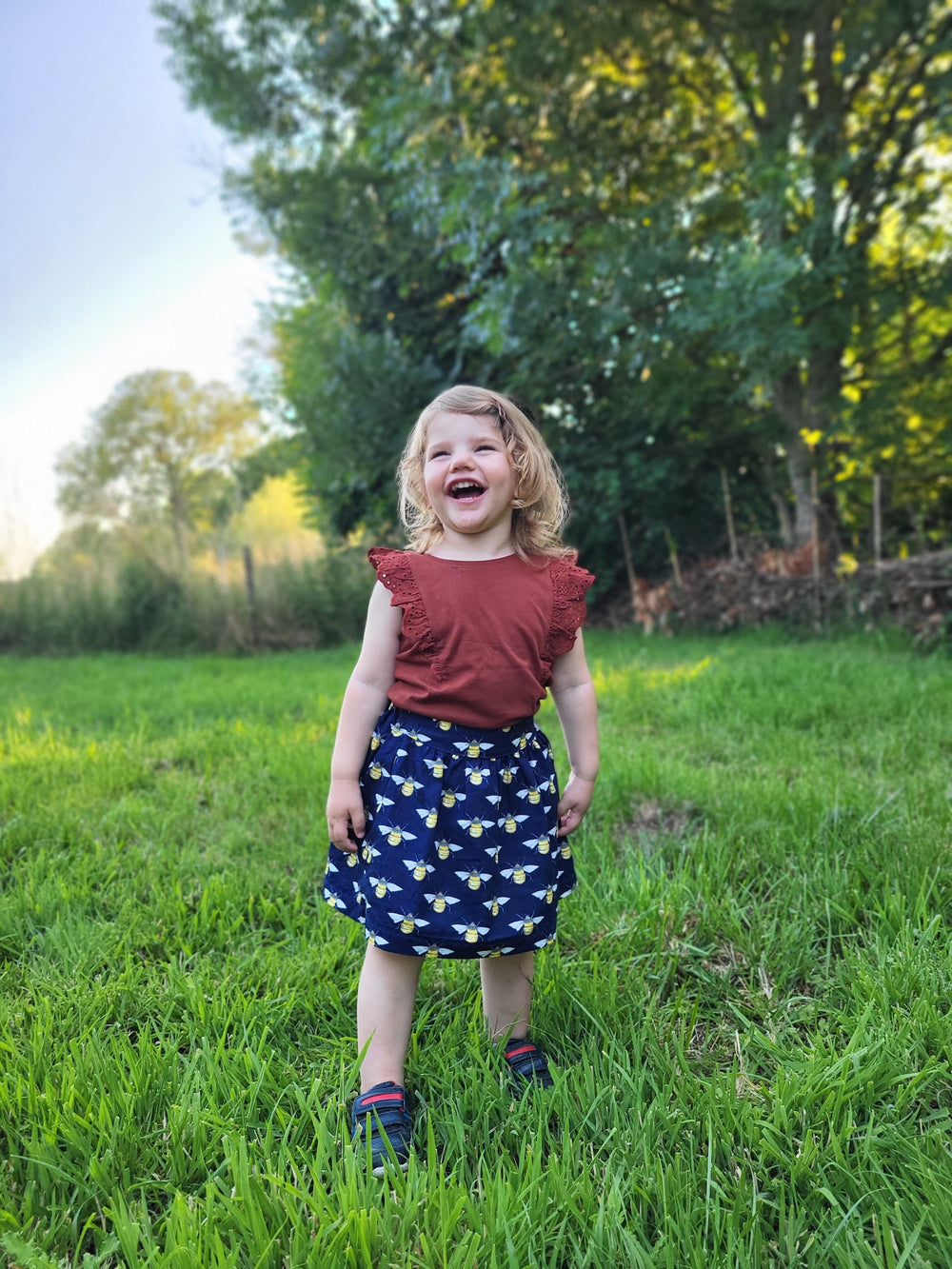 Girl wearing the Children's Eucalyptus Skirt sewing pattern from Waves & Wild on The Fold Line. A skirt pattern made in cotton poplin or linen fabric, featuring an elasticated waist with a flat front, pockets, and knee length.