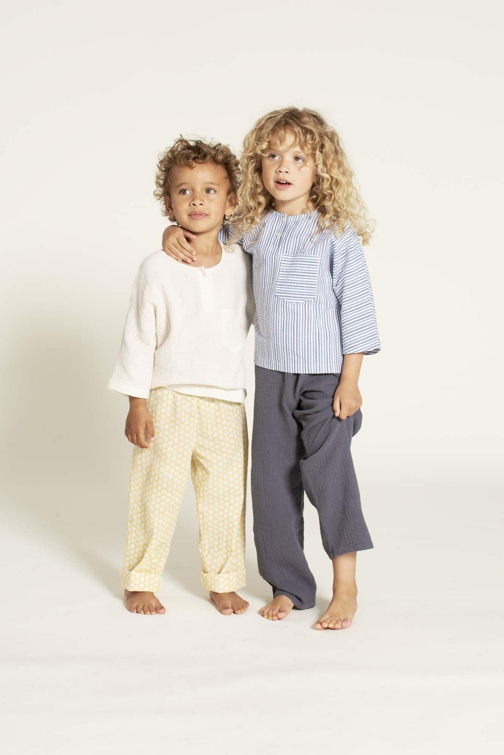 Children wearing the Children's PJ Pants sewing pattern from Wardrobe by Me on The Fold Line. A pyjama pants pattern made in cotton, silk, or viscose fabric, featuring a relaxed fit, elastic and drawstring waist, and full length legs.