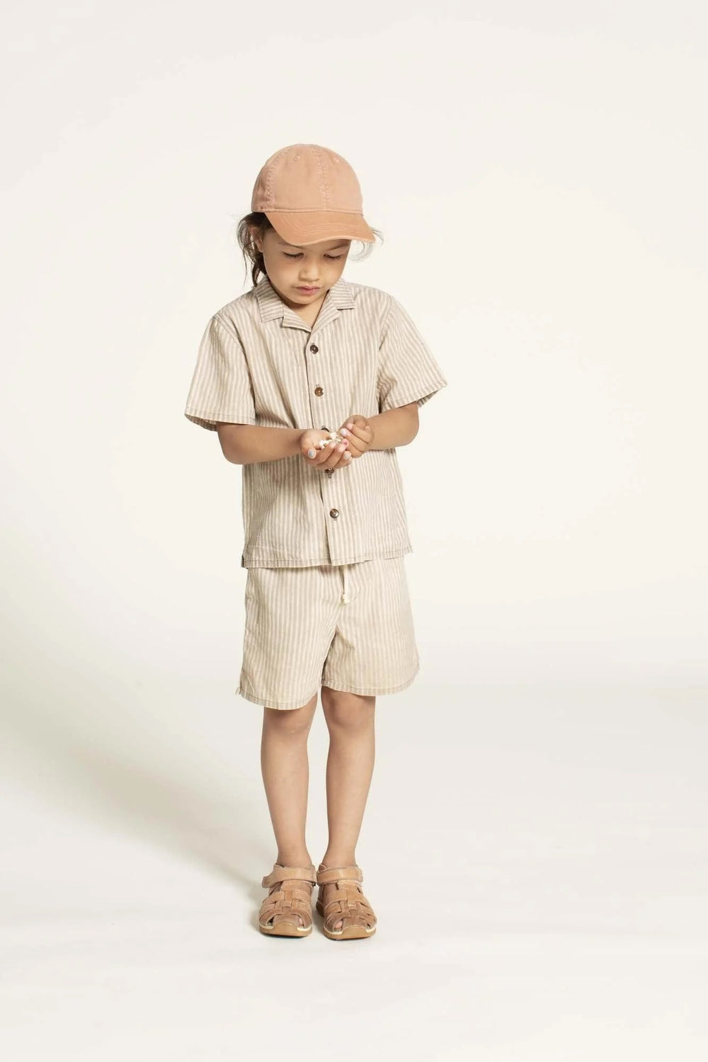 Child wearing the Children’s Tropical Shirt sewing pattern from Wardrobe by Me on The Fold Line. A shirt pattern made in cotton, viscose, or linen fabric, featuring a convertible collar, button front, short sleeves, and side slits.