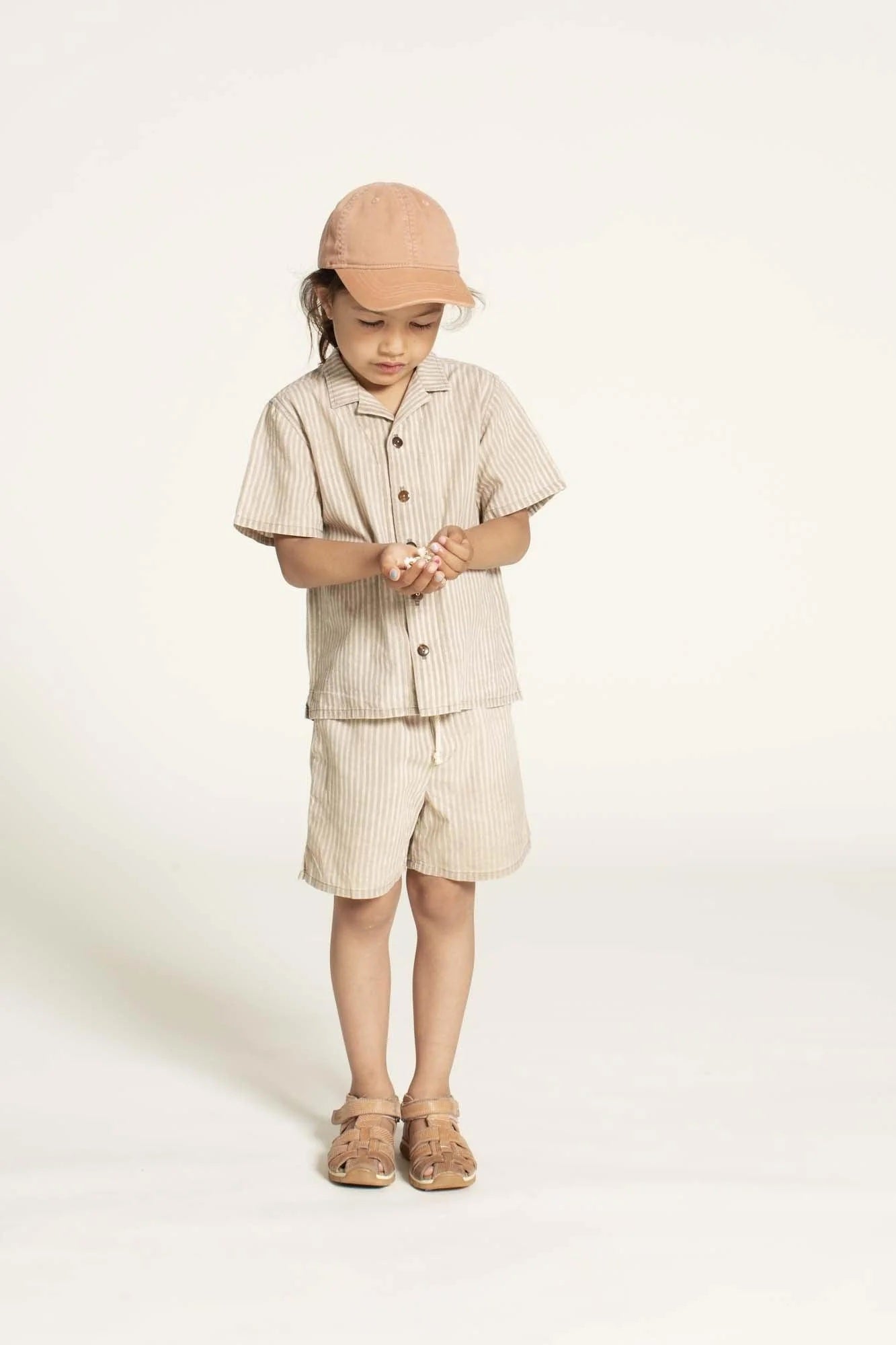 Child wearing the Children’s Tropical Shirt sewing pattern from Wardrobe by Me on The Fold Line. A shirt pattern made in cotton, viscose, or linen fabric, featuring a convertible collar, button front, short sleeves, and side slits.