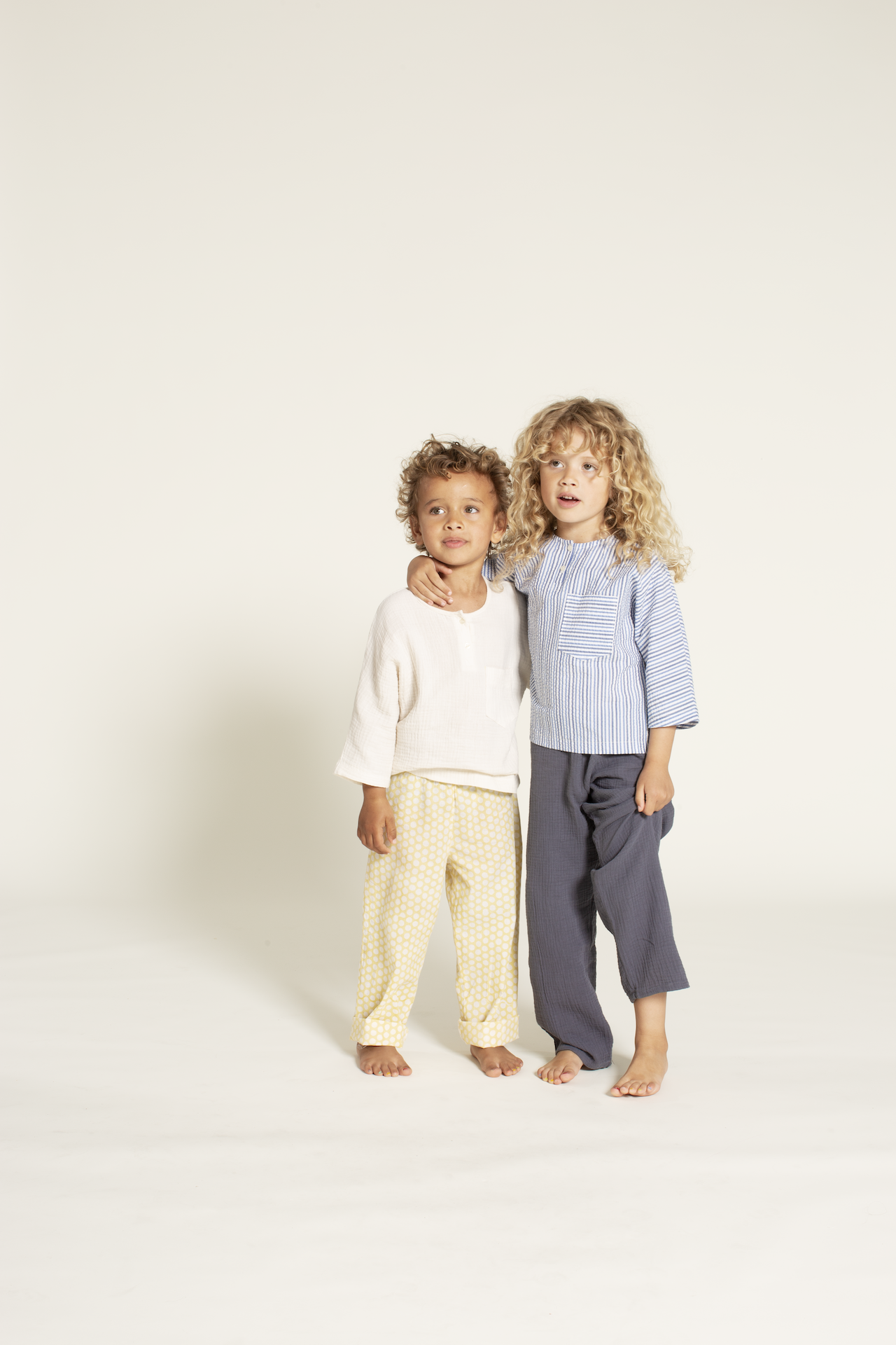 Children wearing the Children's Una Shirt sewing pattern from Wardrobe by Me on The Fold Line. A top pattern made in cotton fabric, featuring a relaxed fit, round neckline, button placket, chest pocket, and long sleeves.