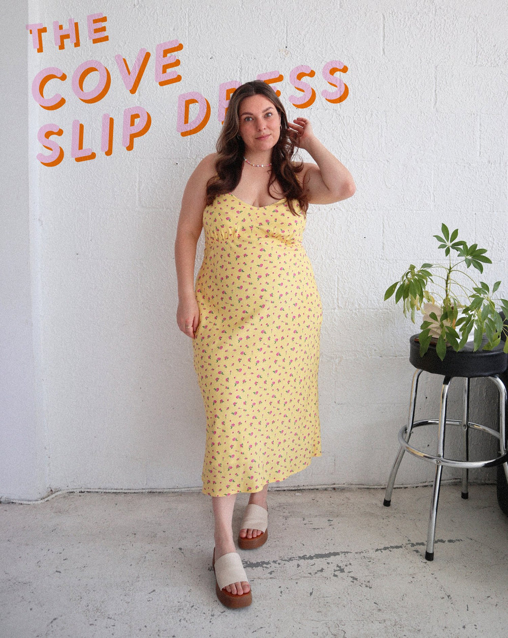 Woman wearing the Cove Slip Dress sewing pattern from Les Perlines on The Fold Line. A sleeveless dress pattern made in silk, satin, rayon, or viscose fabric, featuring a bias cut, low neckline, thin straps, gathers under the bust, and midi length.
