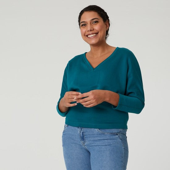 Woman wearing the Ebène Top sewing pattern from Coralie Bijasson on The Fold Line. A sweater pattern made in French terry, jersey, or knit fabric, featuring a relaxed fit, V-neck, and long batwing sleeves.