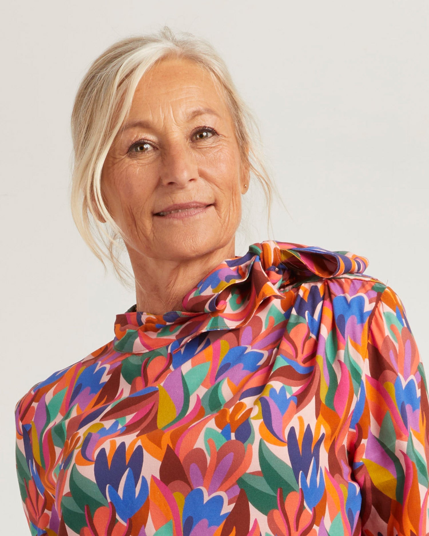 Woman wearing the Elena Blouse sewing pattern from Coralie Bijasson on The Fold Line. A blouse pattern made in viscose crepe, silk satin, or light cotton fabric, featuring a pussy bow collar, pleated shoulder, and long sleeves with three-button cuffs.