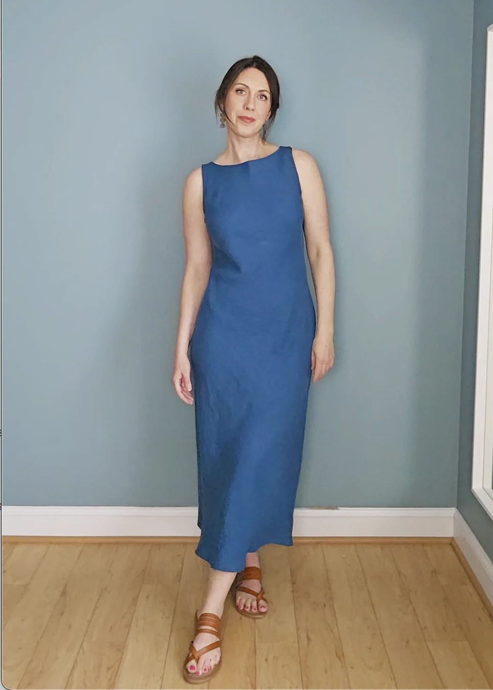 Woman wearing the Ella Dress sewing pattern from Pattern Scout on The Fold Line. A sleeveless shift dress pattern made in rayon, linen, silk, or satin fabric, featuring a boat neckline, bias cut, and midi length.