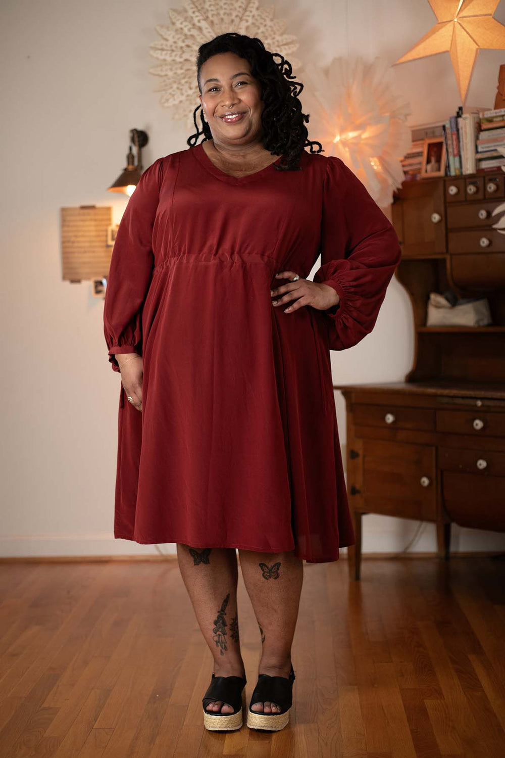 Woman wearing the Ember Dress sewing pattern from Sew Liberated on The Fold Line. A dress pattern made in rayon challis, cotton poplin, chambray, viscose, silk charmeuse, or linen fabric, featuring a V-neckline, princess seams, long bishop sleeves, ties to gather the waist, side seam pockets, and midi length.