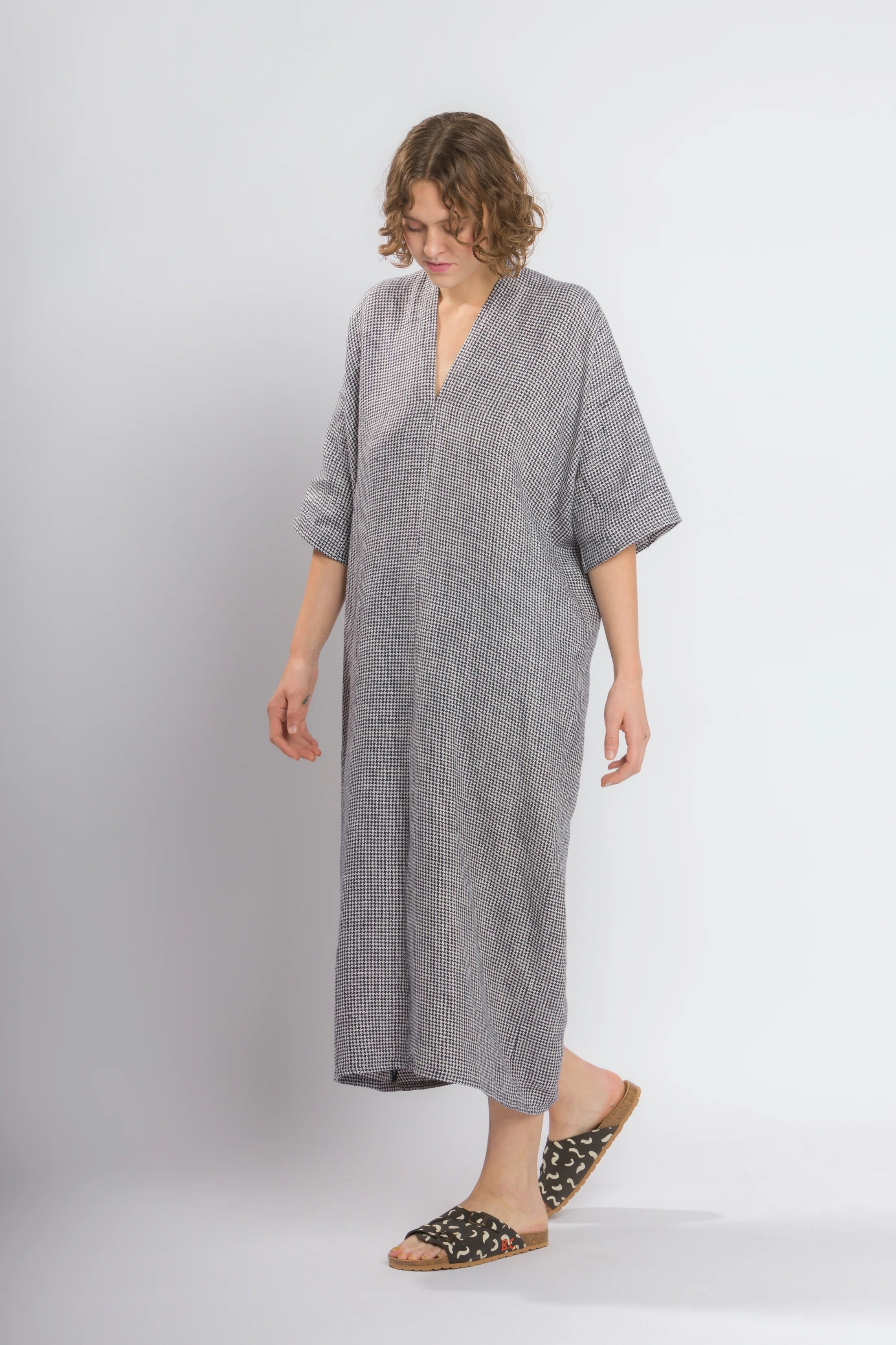 Woman wearing the Envelope Dress Hack Pack sewing pattern from Cris Wood Sews on The Fold Line. A dress pattern made in linen, rayon, silk, viscose blend, or lightweight cotton fabric, featuring a relaxed fit, deep v-neckline, mid-length sleeves, and midi length.