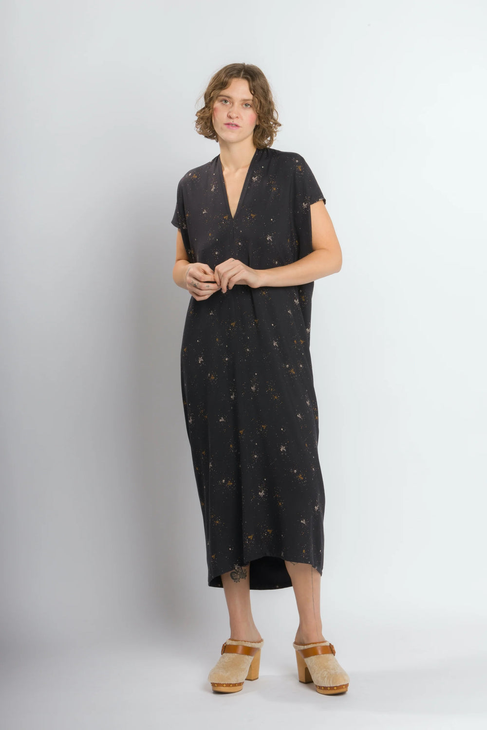 Woman wearing the Envelope Dress sewing pattern from Cris Wood Sews on The Fold Line. A dress pattern made in linen, rayon, silk, viscose blend, or lightweight cotton fabric, featuring caftan styling, a V-neck, short sleeves, high-low hem, and midi length.