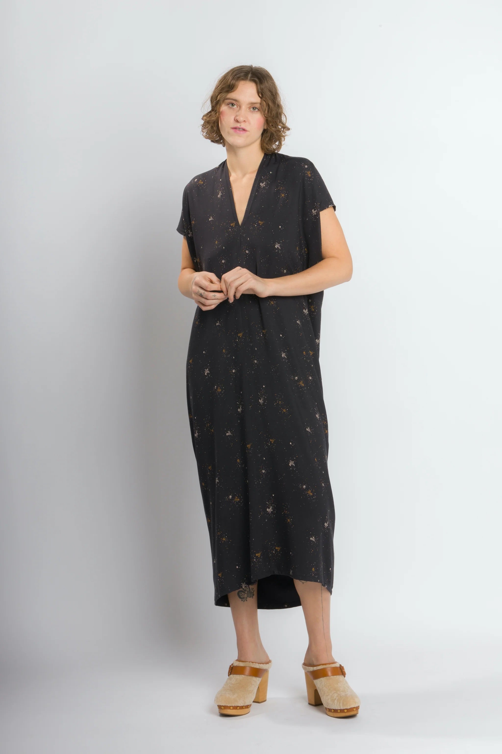Woman wearing the Envelope Dress sewing pattern from Cris Wood Sews on The Fold Line. A dress pattern made in linen, rayon, silk, viscose blend, or lightweight cotton fabric, featuring caftan styling, a V-neck, short sleeves, high-low hem, and midi length.