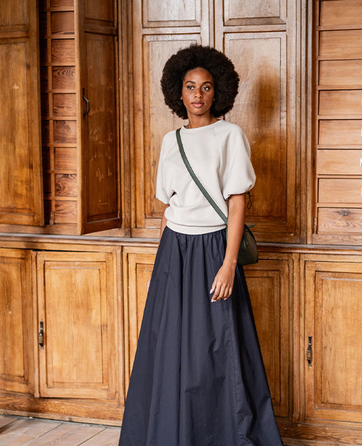 Woman wearing the Esha Sweatshirt sewing pattern from Fibre Mood on The Fold Line. A sweatshirt pattern made in French terry, neoprene, scuba, interlock, knit jacquard, or sweater fabric, featuring a relaxed fit, round front neckline, back V-neckline, and mid-length puff raglan sleeves with elastic cords and cord stoppers.