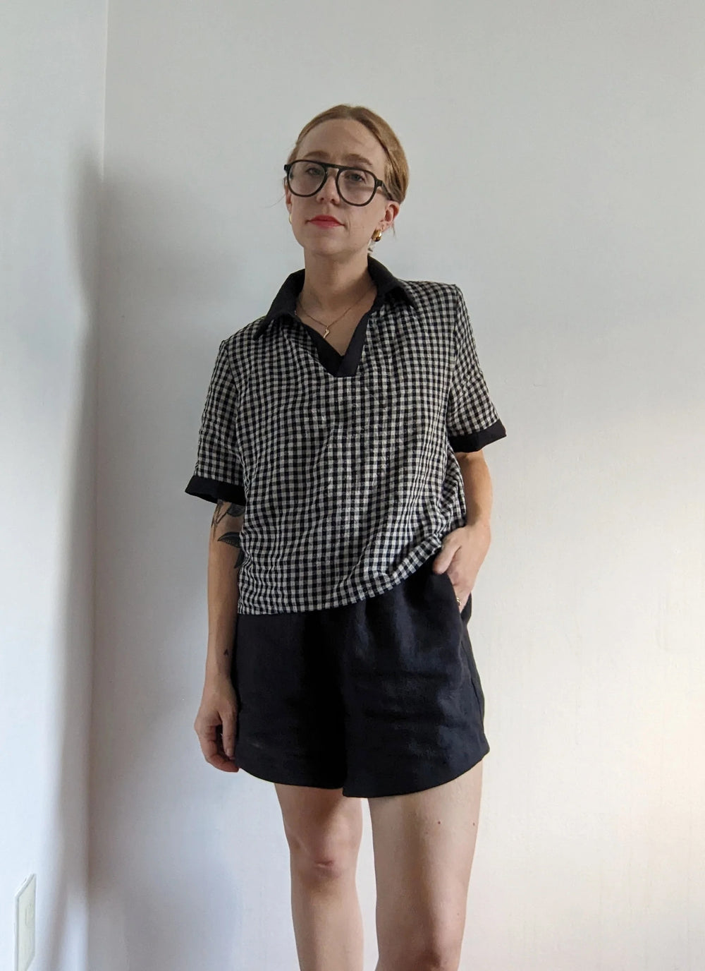 Woman wearing the Felix Top sewing pattern from Spaghetti Western Sewing on The Fold Line. A top pattern made in cotton poplin, voile, lawn, batiste, linen, double gauze, or washed cotton fabric, featuring a boxy cut, contrast collar, V-neck partial placket, and elongated short sleeves.