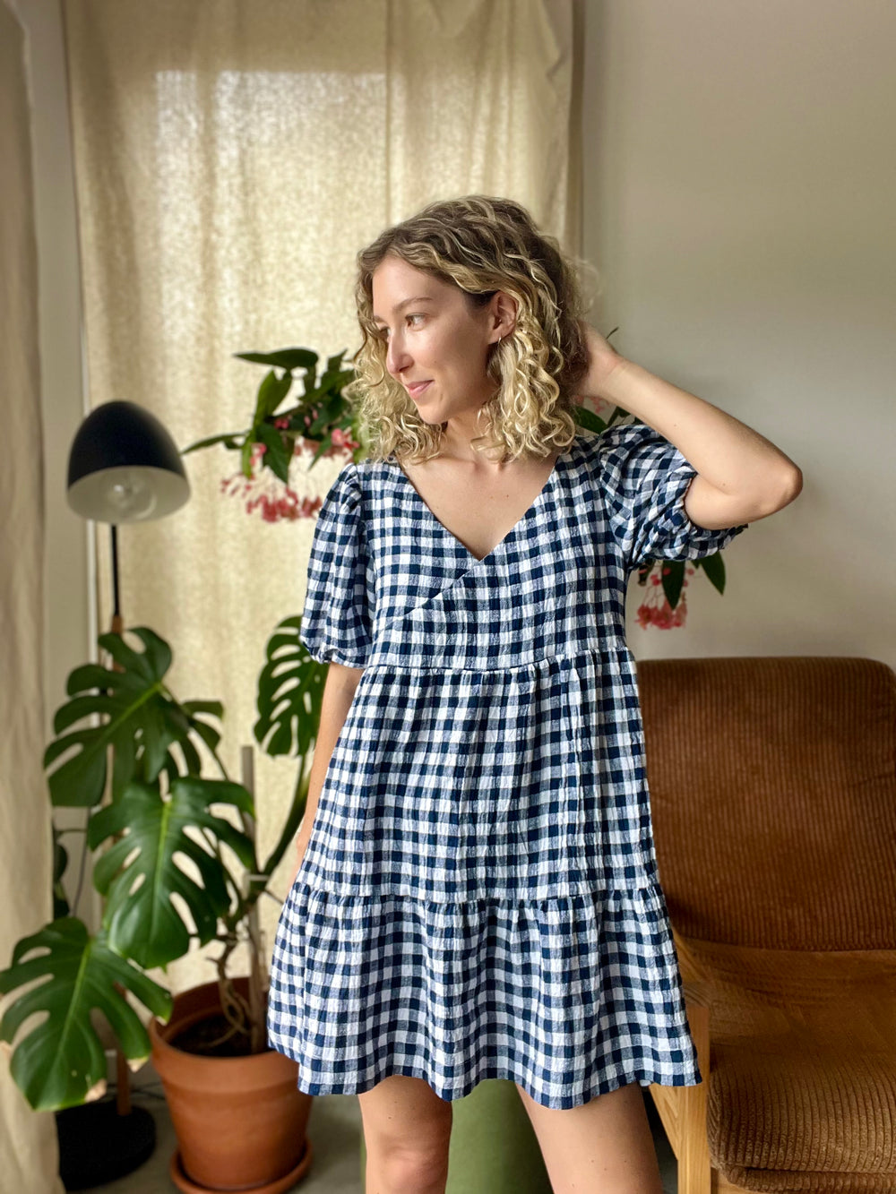 Woman wearing the Frankie Dress sewing pattern from Elle Stitch on The Fold Line. A mini dress pattern made in lightweight linen, crinkle linen, cotton lawn, or linen rayon blend fabric, featuring a relaxed fit, self-lined crossover bodice, short puff sleeves, and a two-tier gathered skirt.