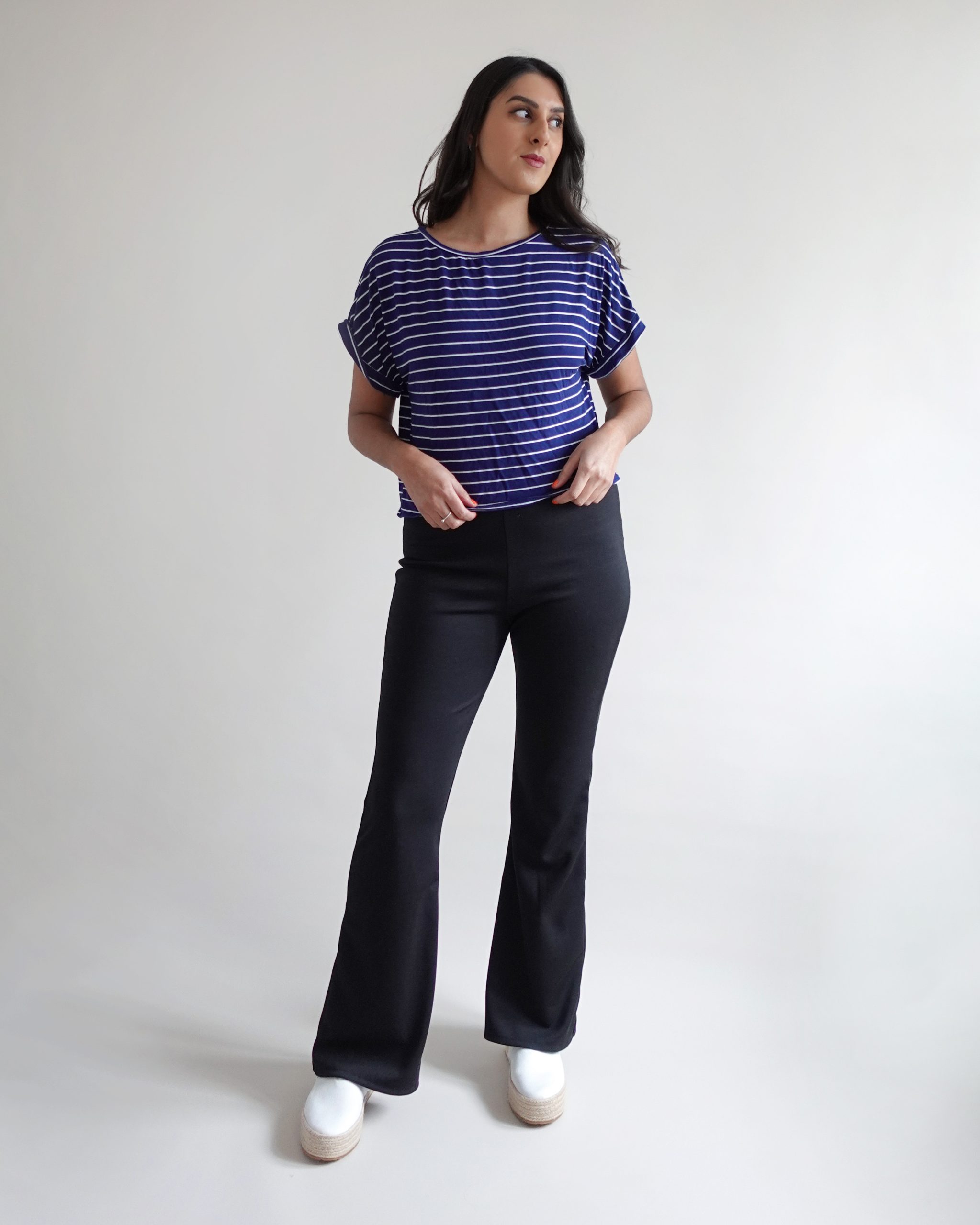Woman wearing the Freya Flare Trousers sewing pattern from Tammy Handmade on The Fold Line. A trousers pattern made in jersey, ribbed knit, sweater knit, or ponte roma fabric, featuring a high waist, elasticated waistband, and flared leg.