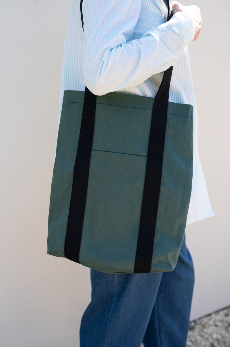 Woman with the Griffin Tote Bag sewing pattern from Bobbins and Buttons on The Fold Line. A bag pattern made in denim or cotton drill fabric, featuring a full lining, front pocket, and webbing straps.