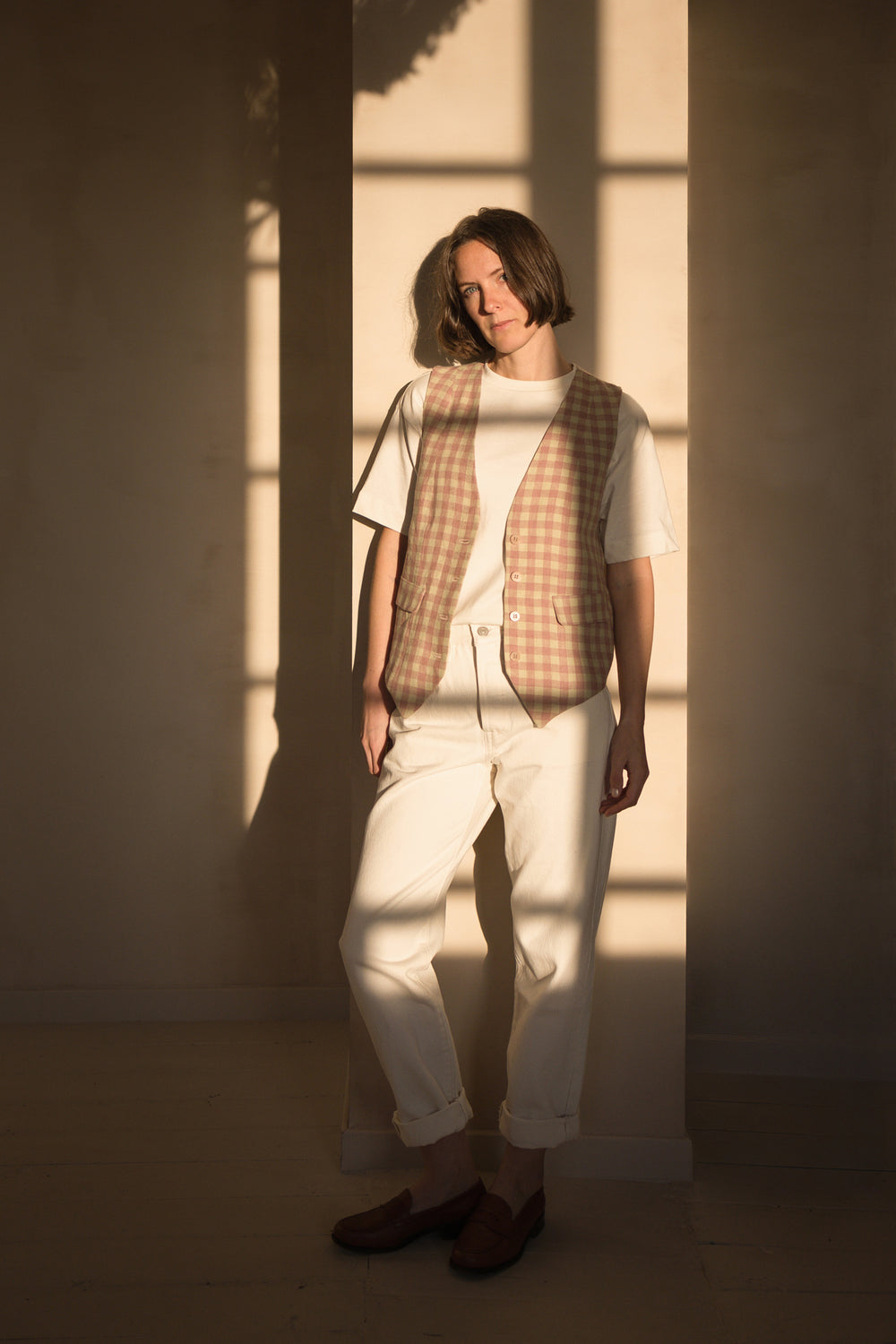 Woman wearing the Harold Vest sewing pattern from Ready to Sew on The Fold Line. A waistcoat pattern made in tencel twill, wool, lightweight denim, or linen fabric, featuring a classic cut, faux welt pockets, button front, and knit back.