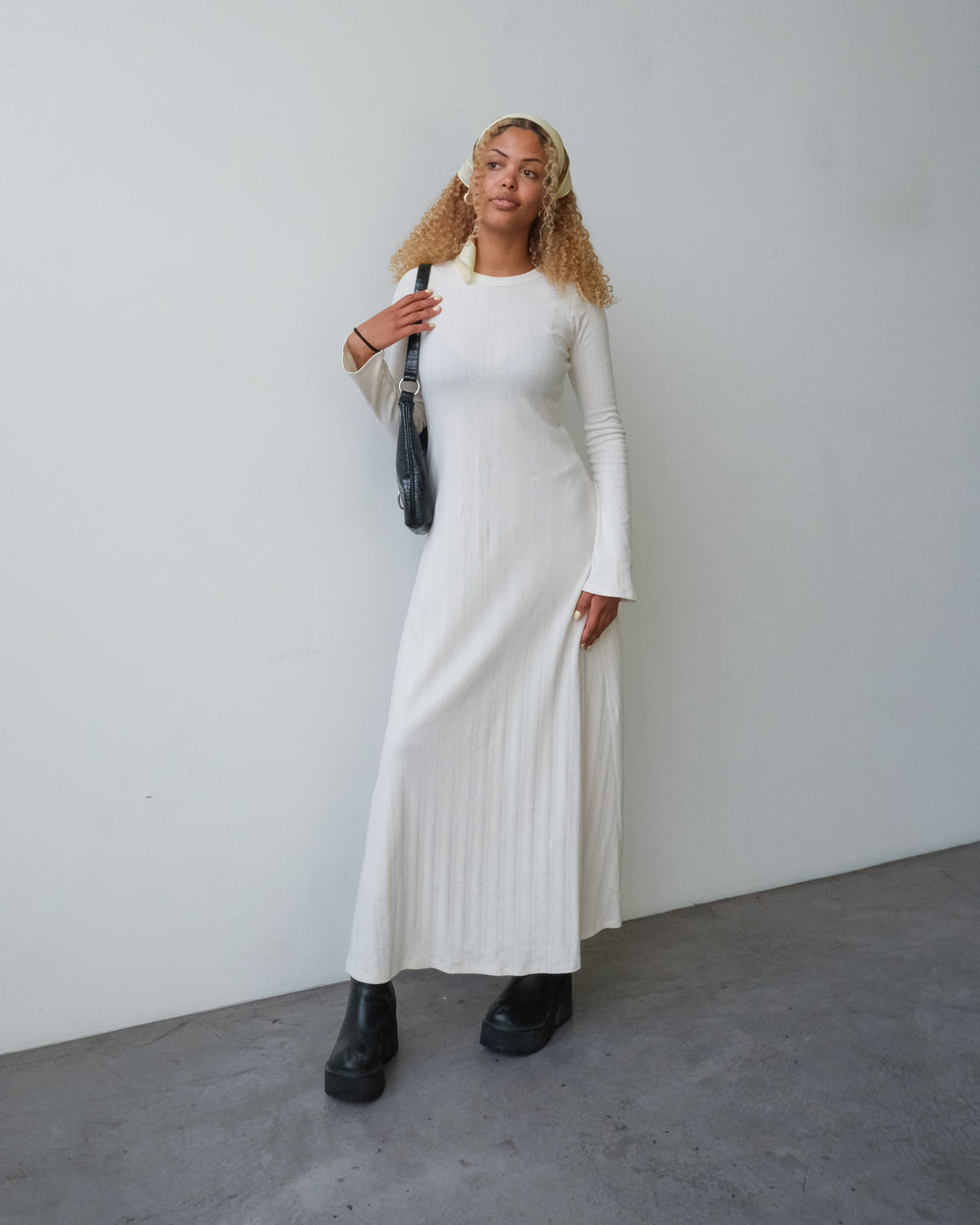 Woman wearing the Honeygirl Dress Expansion sewing pattern from Paradise Patterns on The Fold Line. A dress pattern made in pointelle knit, cotton double knit, or rib knit fabric, featuring a round neckline, long bell sleeves, and a maxi length.