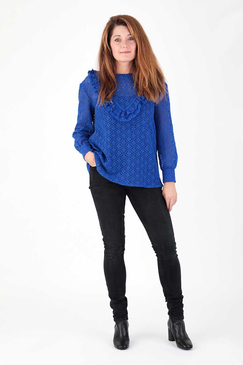 Woman wearing the Kiki Ruffle Shirt sewing pattern from Schnittchen Patterns on The Fold Line. A top pattern made in sweatshirt, denim, silk, or lace fabric, featuring a round neckline, two rows of ruffles, and long sleeves with cuffs.