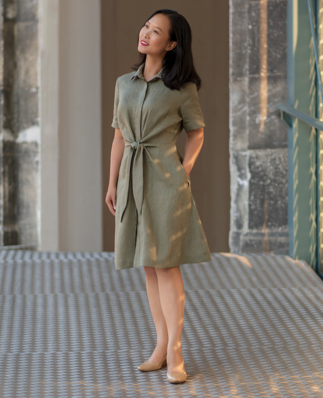 Woman wearing the Ladera Dress sewing pattern from Itch to Stitch on The Fold Line. A shirt dress pattern made in linen, linen blend, twill or broadcloth fabric, featuring a classic collar, hidden front button placket, front tie, short cuffed sleeves, side pockets, and knee length.