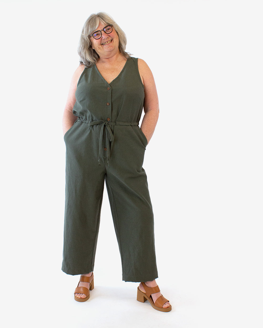 Woman wearing the Lazo Jumpsuit sewing pattern from Helen's Closet on The Fold Line. A sleeveless jumpsuit pattern made in rayon/viscose challis or poplin, linen, cotton, or tencel fabric, featuring a V-neck, button front closure, drawstring waist, and pockets.