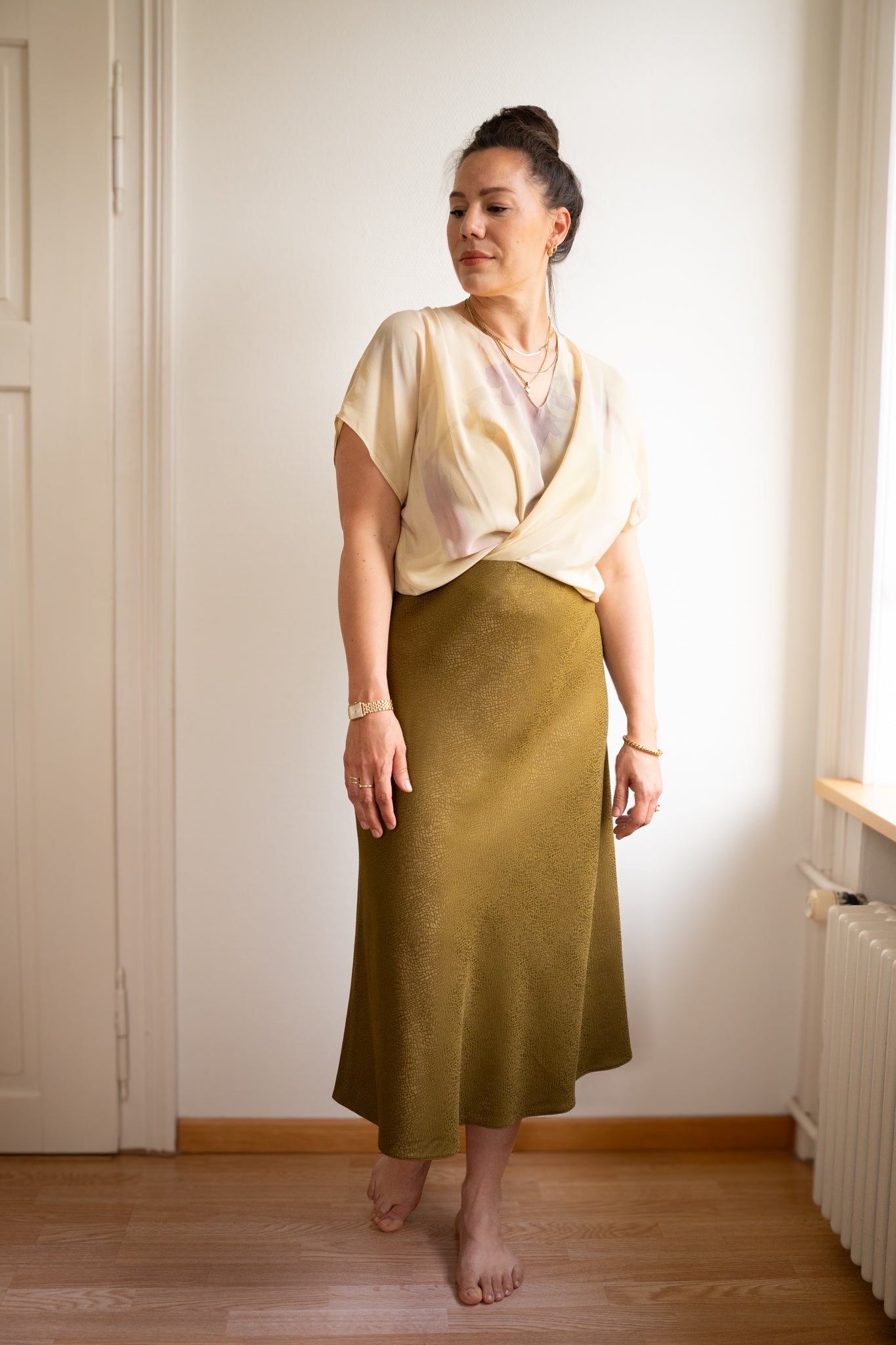 Woman wearing the Lilly Bias Skirt sewing pattern from Sew.lala Patterns on The Fold Line. A skirt pattern made in viscose, crepe, charmeuse, tencel, or silk fabric, featuring a bias cut, elastic waist, optional invisible zipper, and midi length.