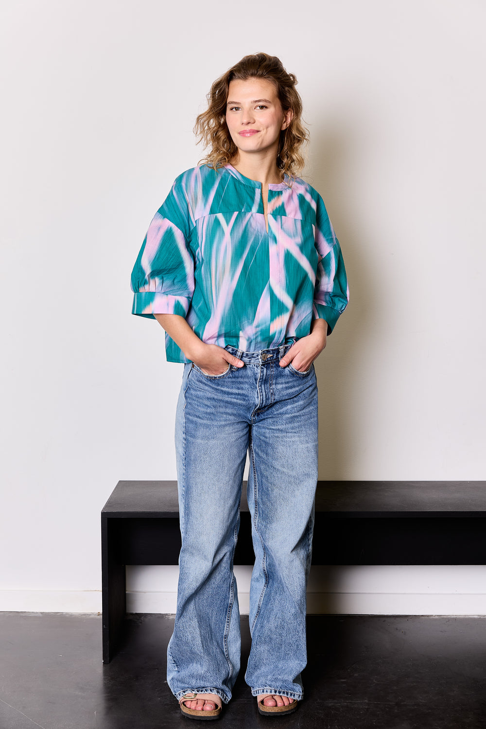 Woman wearing the Lori Blouse sewing pattern from Atelier Jupe on The Fold Line. A top pattern made in viscose, cotton, tencel, double gauze or linen fabric, featuring an oversized fit, front and back yokes, and wide elbow-length sleeves with pleats and cuffs.