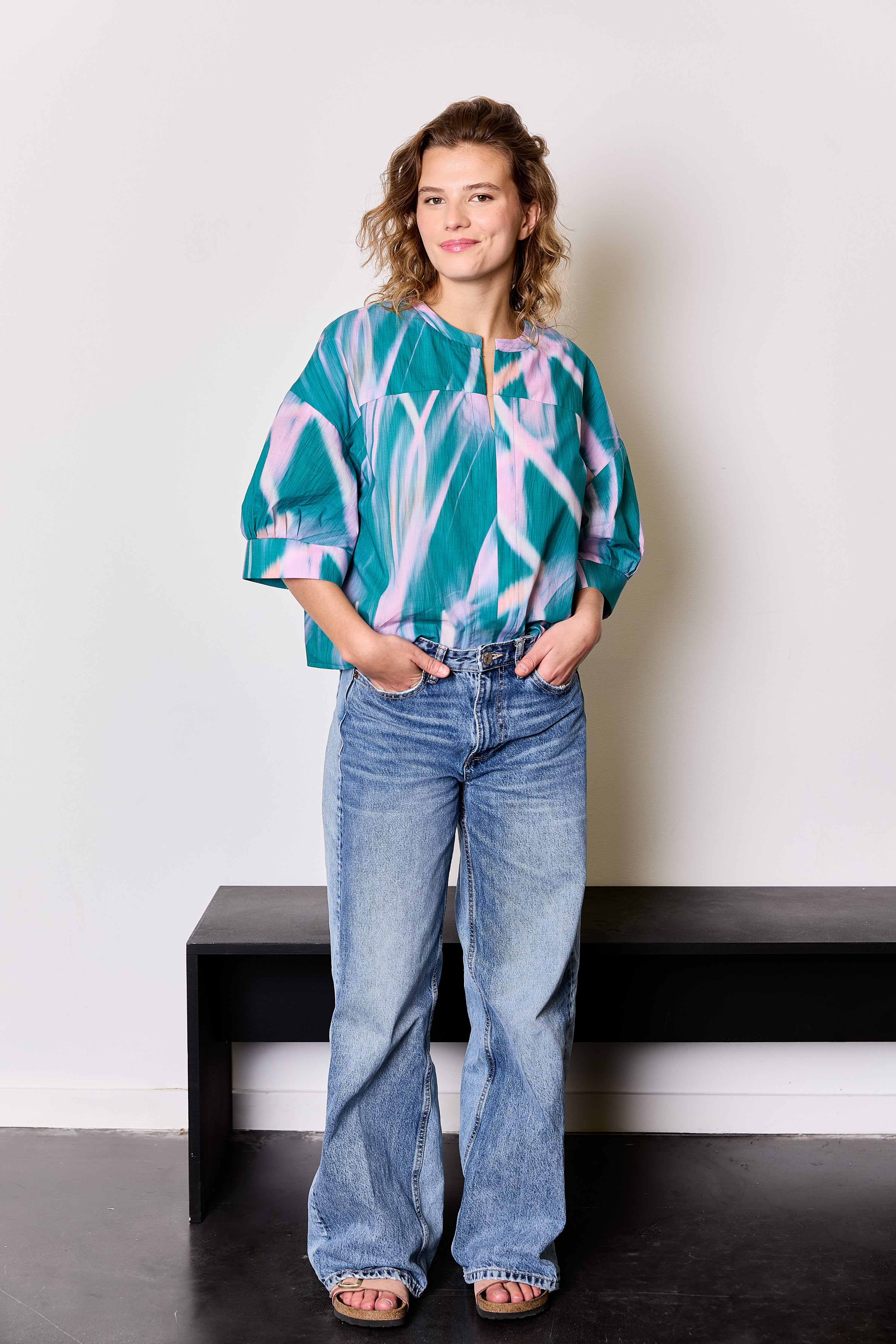 Woman wearing the Lori Blouse sewing pattern from Atelier Jupe on The Fold Line. A top pattern made in viscose, cotton, tencel, double gauze or linen fabric, featuring an oversized fit, front and back yokes, and wide elbow-length sleeves with pleats and cuffs.