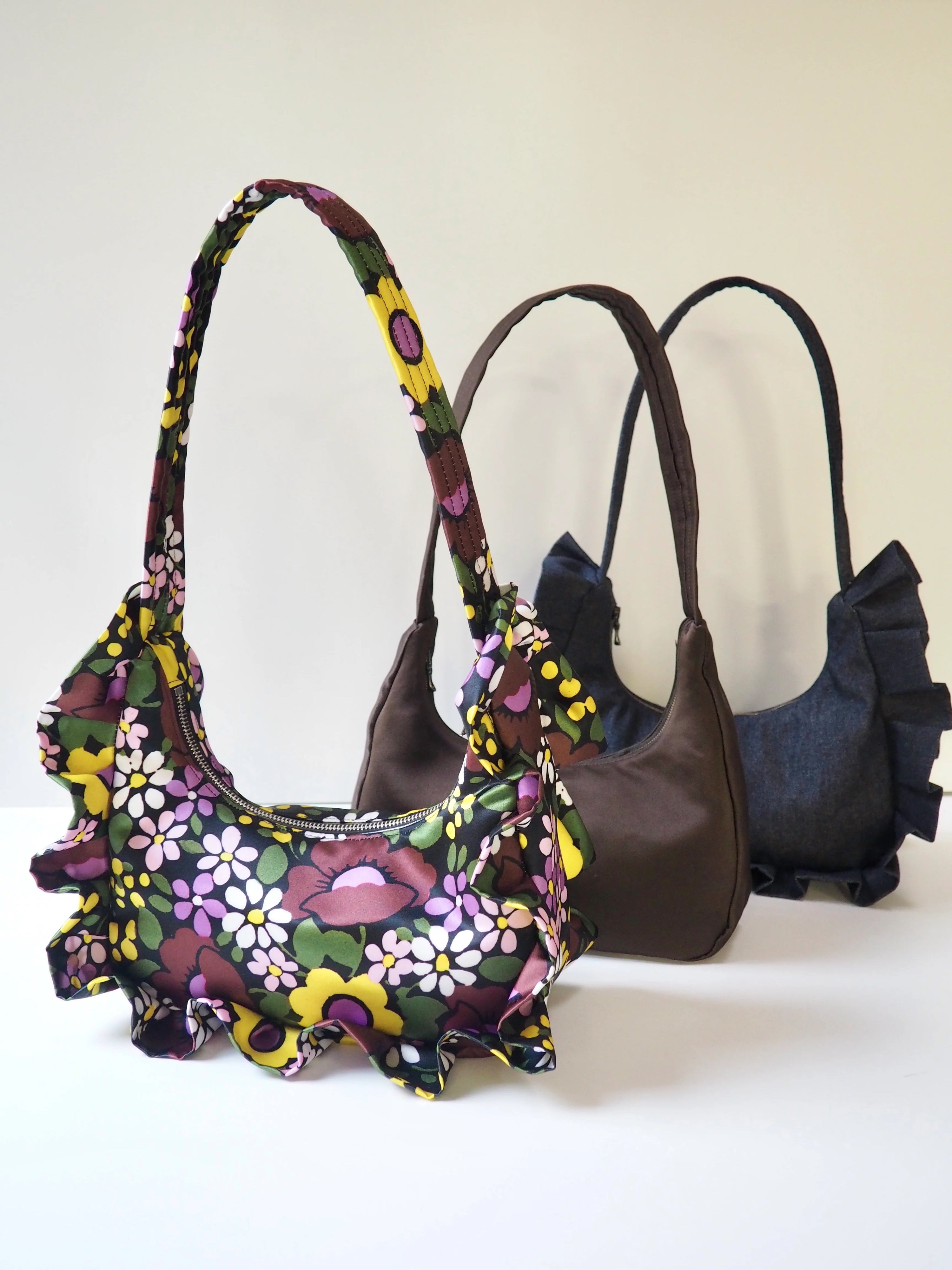 The Lottie Bag sewing pattern from The New Craft House on The Fold Line. A bag pattern made in nylon or ripstop, duchess satin, or denim fabric, featuring a full lining, zip closure, internal pocket, and optional ruffle frill.