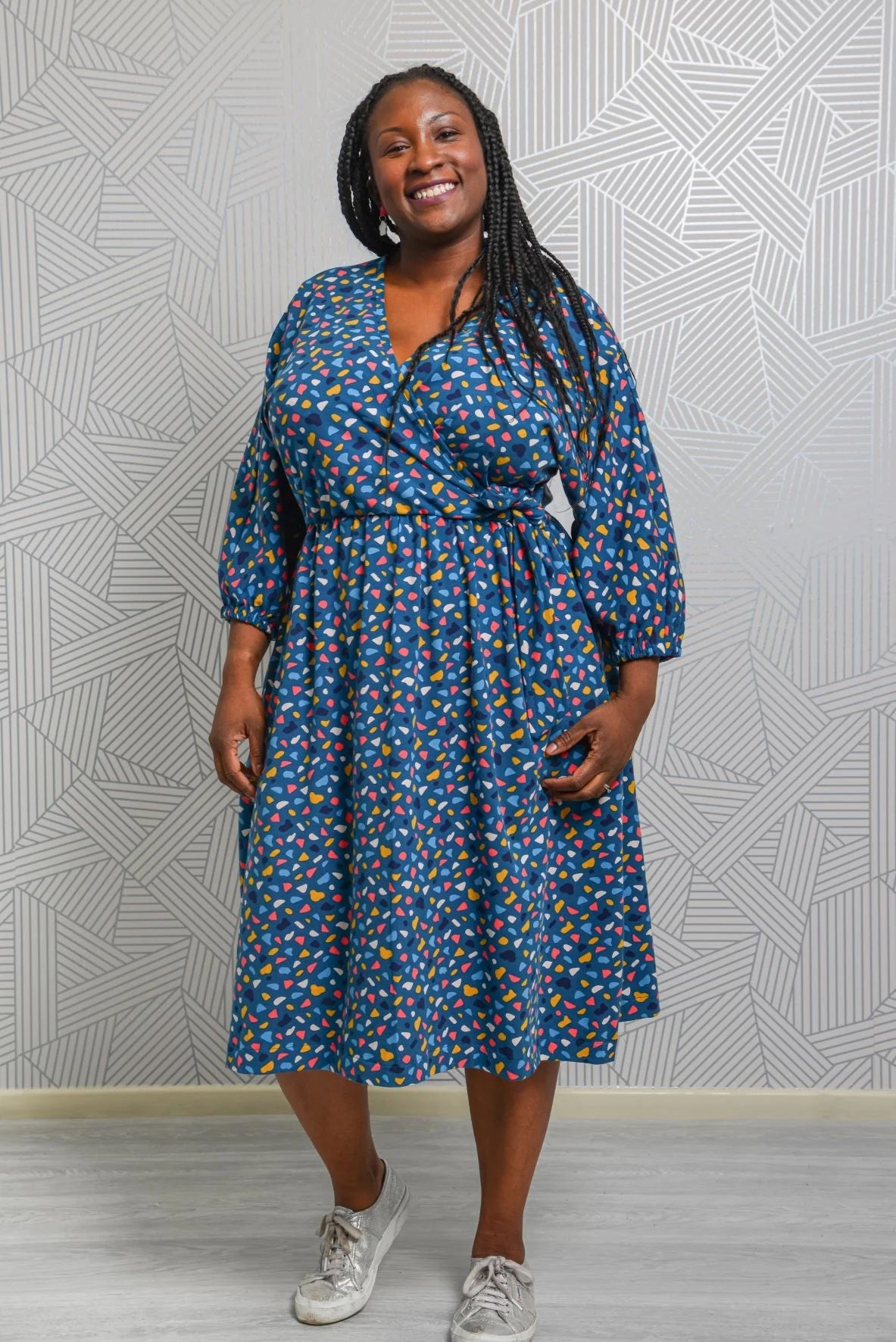 Woman wearing the Margot Dress sewing pattern from Emporia Patterns on The Fold Line. A knit dress pattern made in jersey, lightweight french terry, velour, or ponte roma fabric, featuring a faux wrap bodice, deep V-neck, batwing bracelet-length sleeves, elastic waist, gathered skirt, and in-seam pockets.