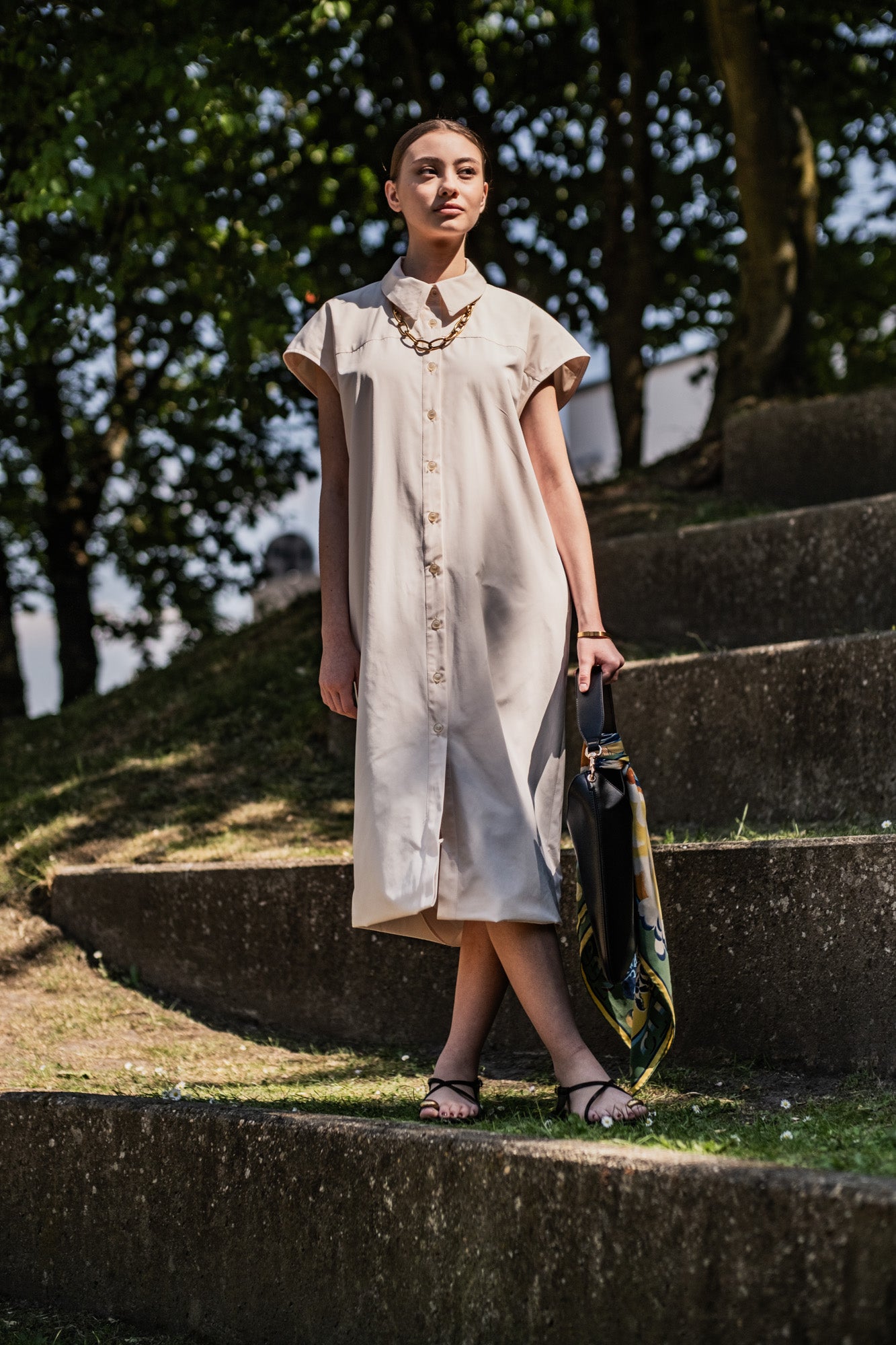 Woman wearing the Marley Dress sewing pattern from Fibre Mood on The Fold Line. A shirt dress pattern made in cotton twill, poplin, nylon, or linen fabric, featuring a relaxed fit, collar and collar stand, double yoke, bias-tape-finished armholes, button front, and midi length.