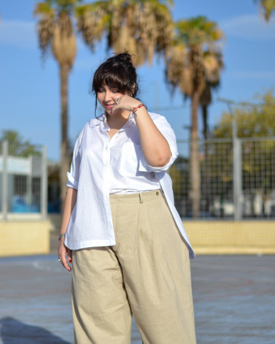 Woman wearing the Mestre Shirt sewing pattern from Pauline Alice on The Fold Line. A shirt pattern made in cotton poplin, chambray, linen, flannel, or silk fabric, featuring a shirt collar, button front, button openings on the sides, long sleeves with asymmetrical cuffs, a double patch pocket on the front, pleat in the back, and curved hem.