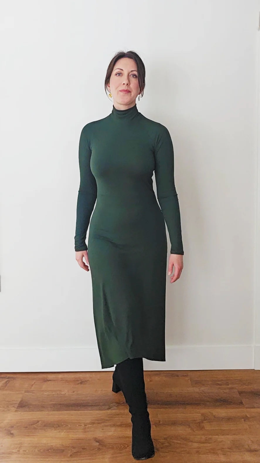 Woman wearing the Mia Dress sewing pattern from Pattern Scout on The Fold Line. A dress pattern made in knit fabric, featuring a fitted silhouette, turtleneck, raglan sleeves, and a fit-and-flare skirt with a midi length high-low hemline.