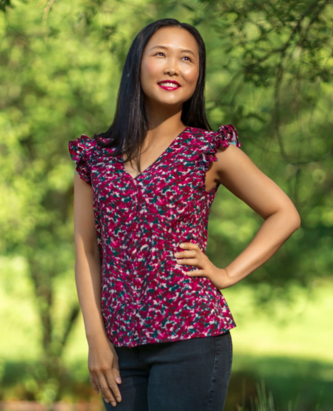 Woman wearing the Mindelo Top sewing pattern from Itch to Stitch on The Fold Line. A sleeveless blouse pattern made in shirting, crepe, challis, or rayon/viscose twill fabric, featuring a V-neckline, button front, and shoulder ruffles.