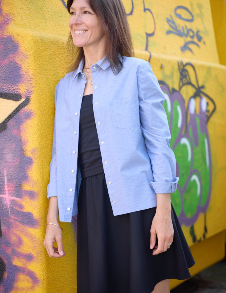 Woman wearing the Must Shirt sewing pattern from Atelier Scämmit on The Fold Line. A shirt pattern made in cotton, linen, silk, or viscose fabric, featuring a classic shirt collar with a collar stand, button placket, long sleeves with cuffs, chest pocket, and straight hem.