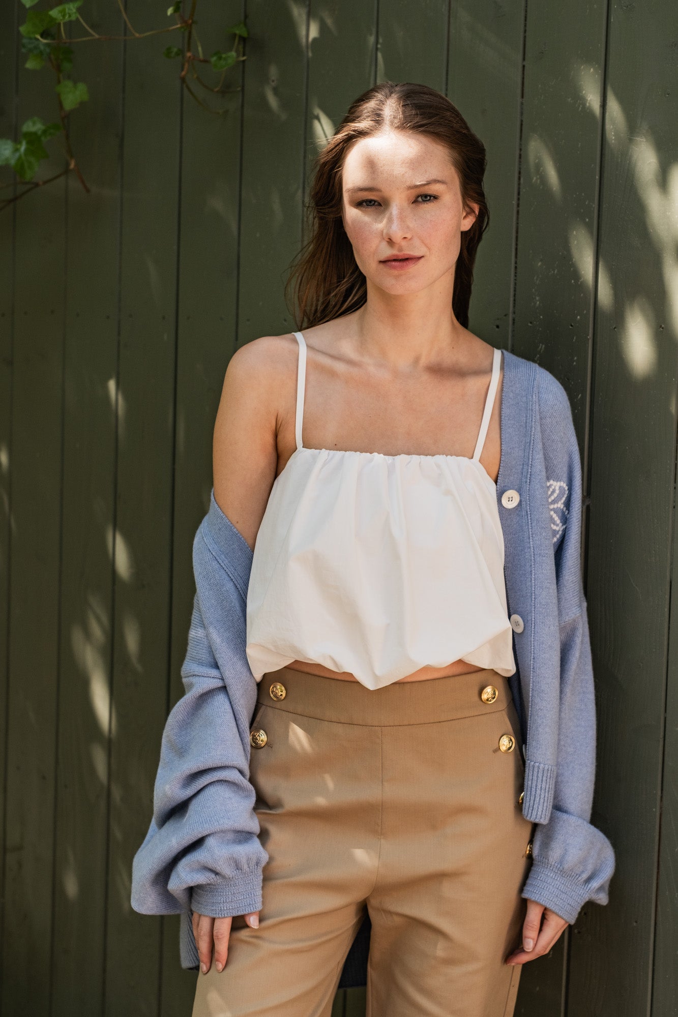 Woman wearing the Nanaka Top sewing pattern from Fibre Mood on The Fold Line. A top pattern made in poplin, satin, linen, nylon, taffeta, or crepe fabric, featuring thin straps, a gathered neckline, balloon hem, and cropped length.